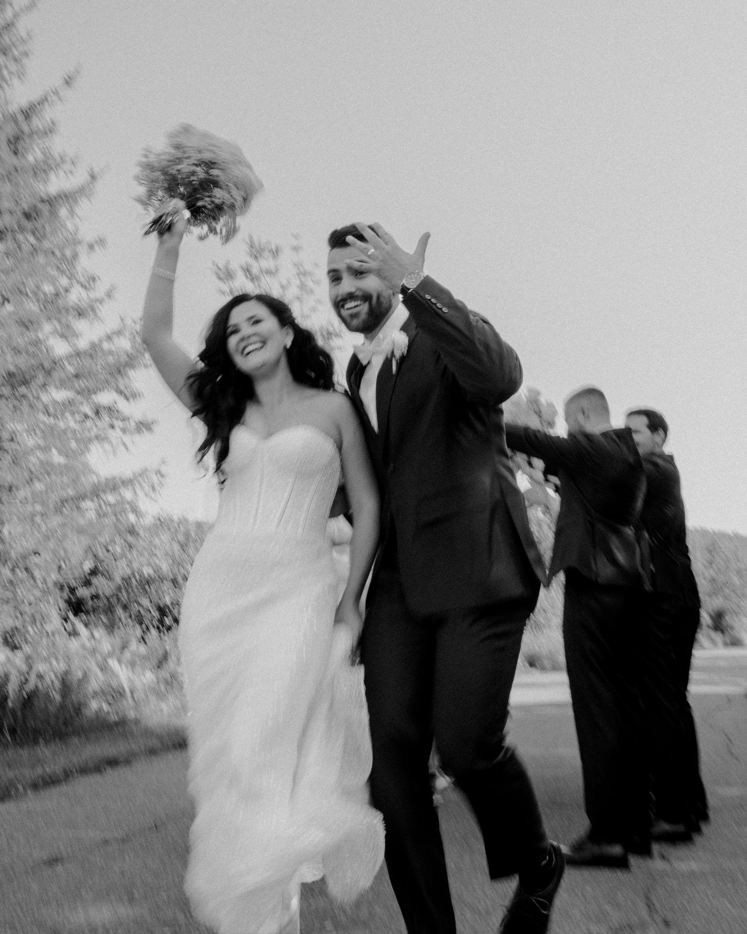A wedding party jumps joyfully in the air outdoors in a series of black and white celebratory photos.