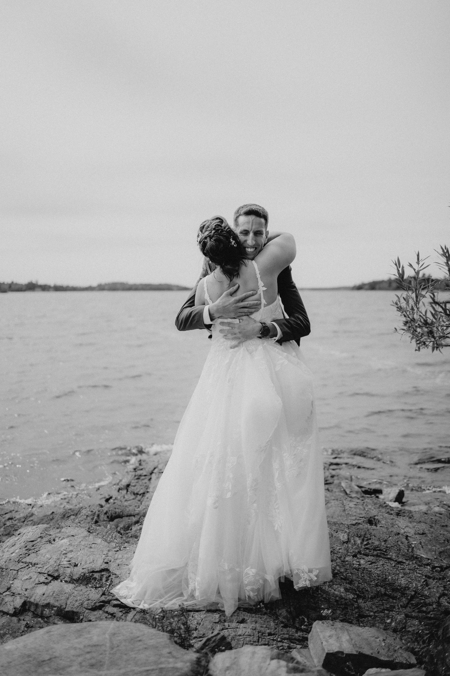 A romantic wedding photoshoot on a rocky beach with dramatic overcast skies.