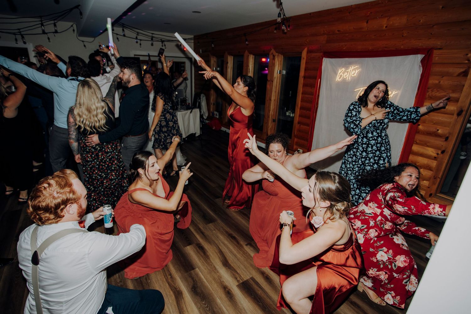 Wedding reception dance party with guests celebrating on wooden dance floor.