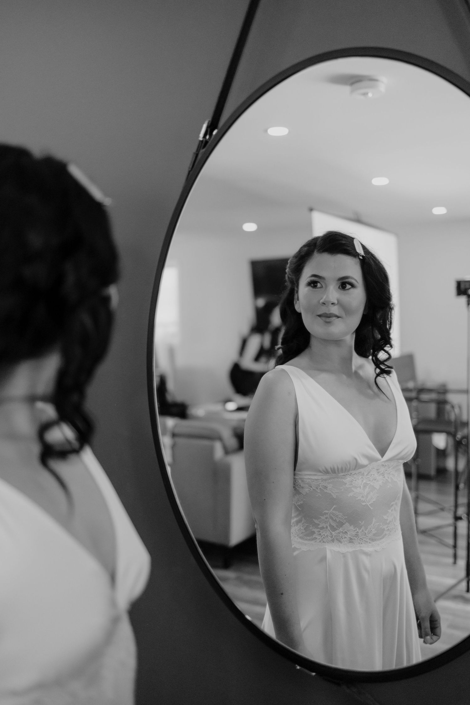 A reflection in a round mirror shows a bride in an elegant white wedding dress.