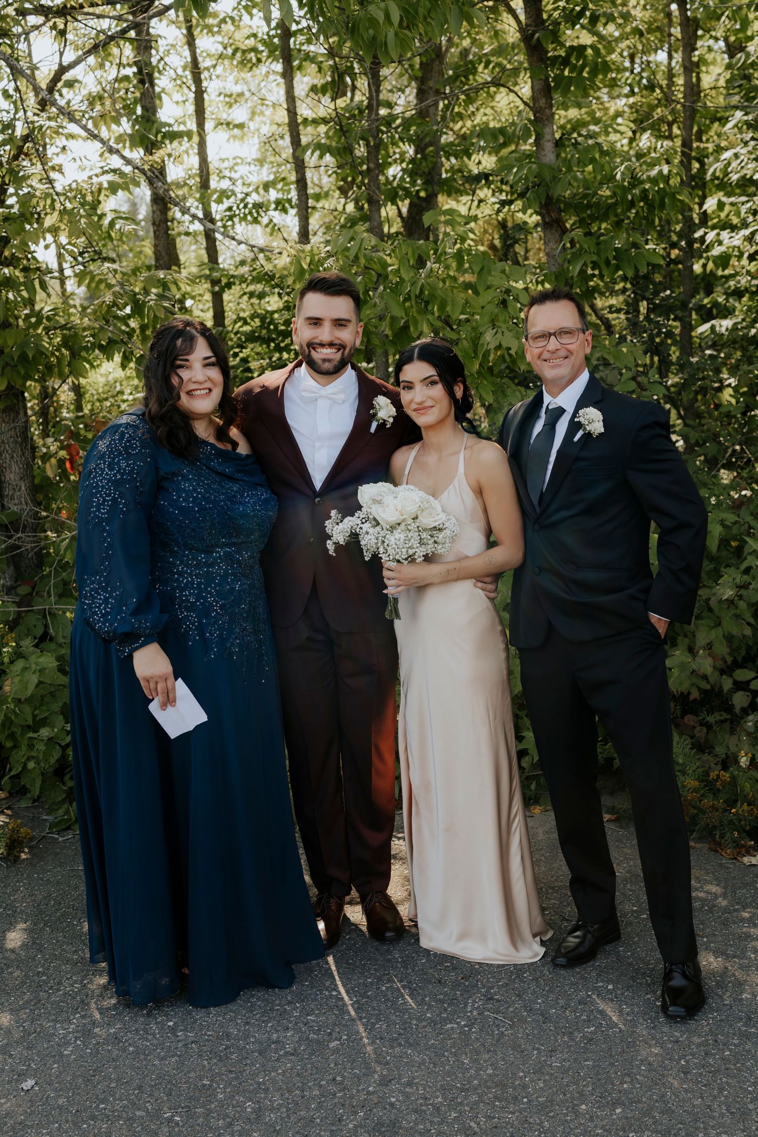 Wedding party in navy and burgundy attire posing outdoors with floral bouquets.