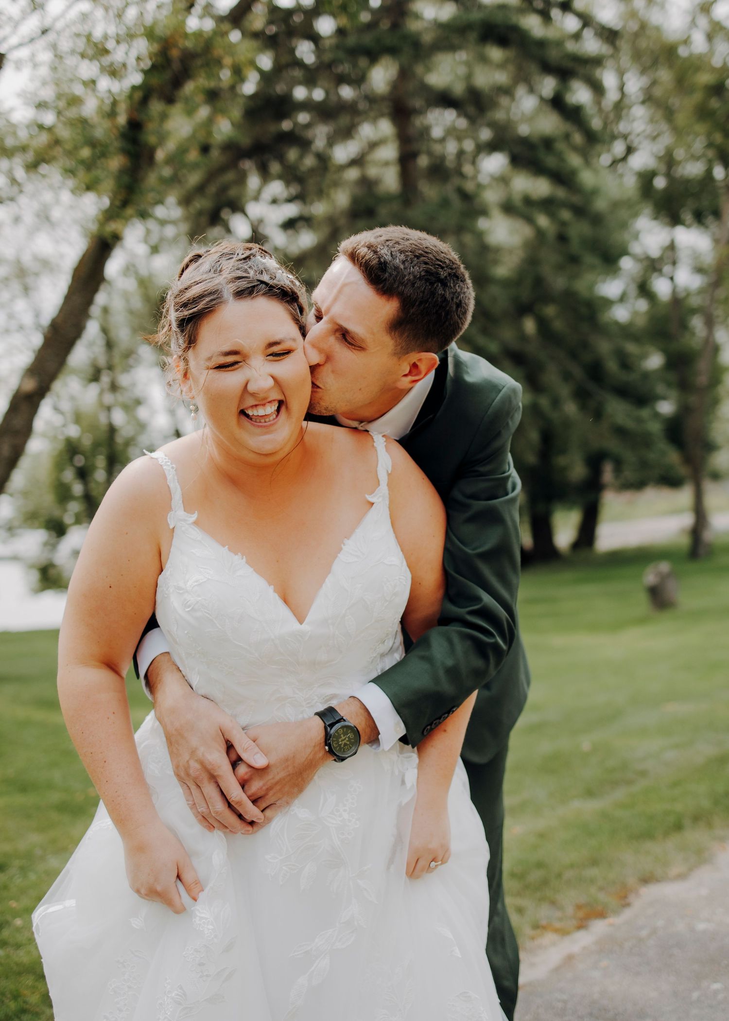 Joyful wedding couple sharing intimate moments on grassy path outdoors.