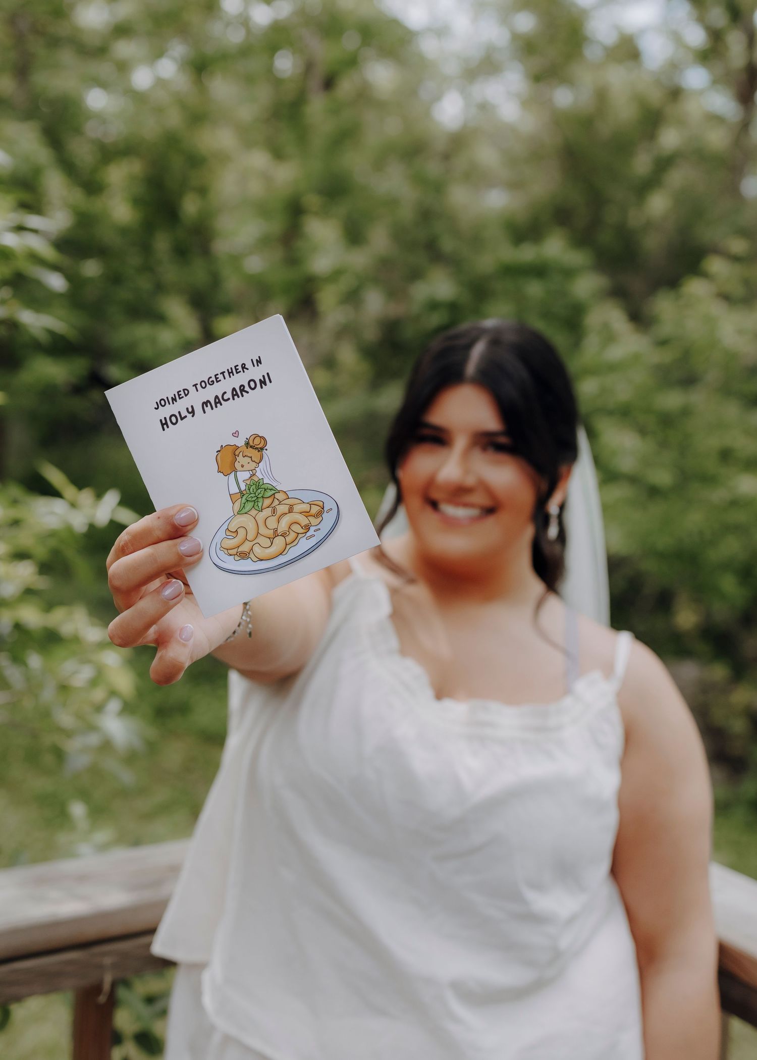 A person in a white wedding dress holds up illustrated cards showing pizza and chicken designs while smiling.