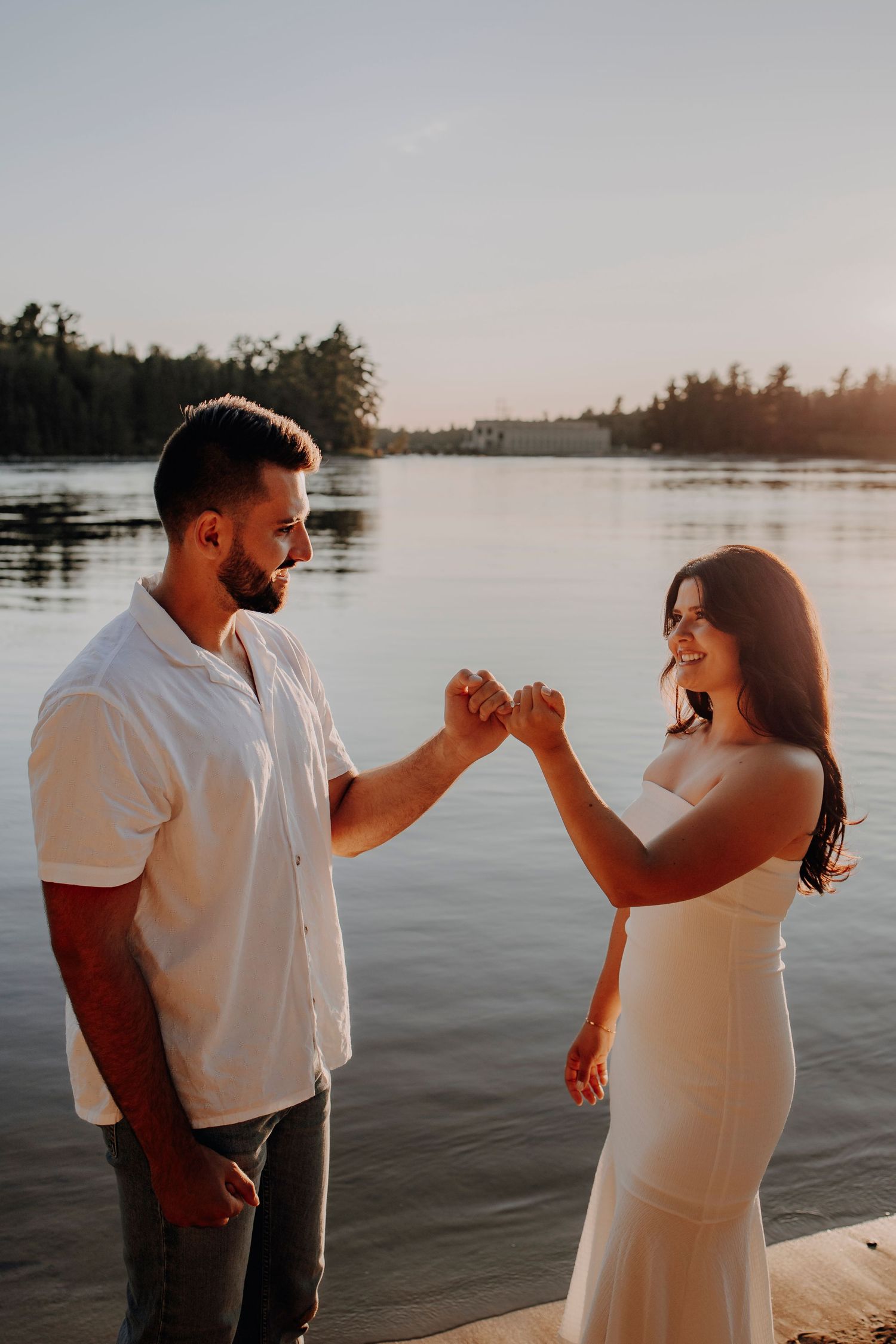 Joyful couple celebrating with a fist bump by the lake during sunset.