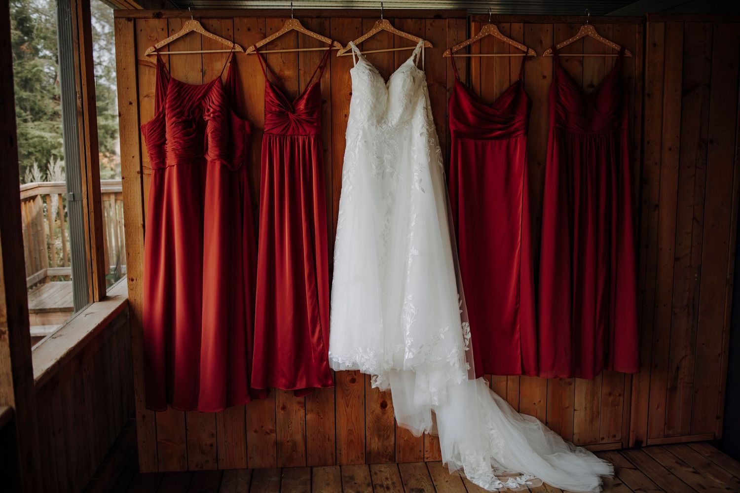 Wedding dresses and burgundy bridesmaid dresses hanging on display.