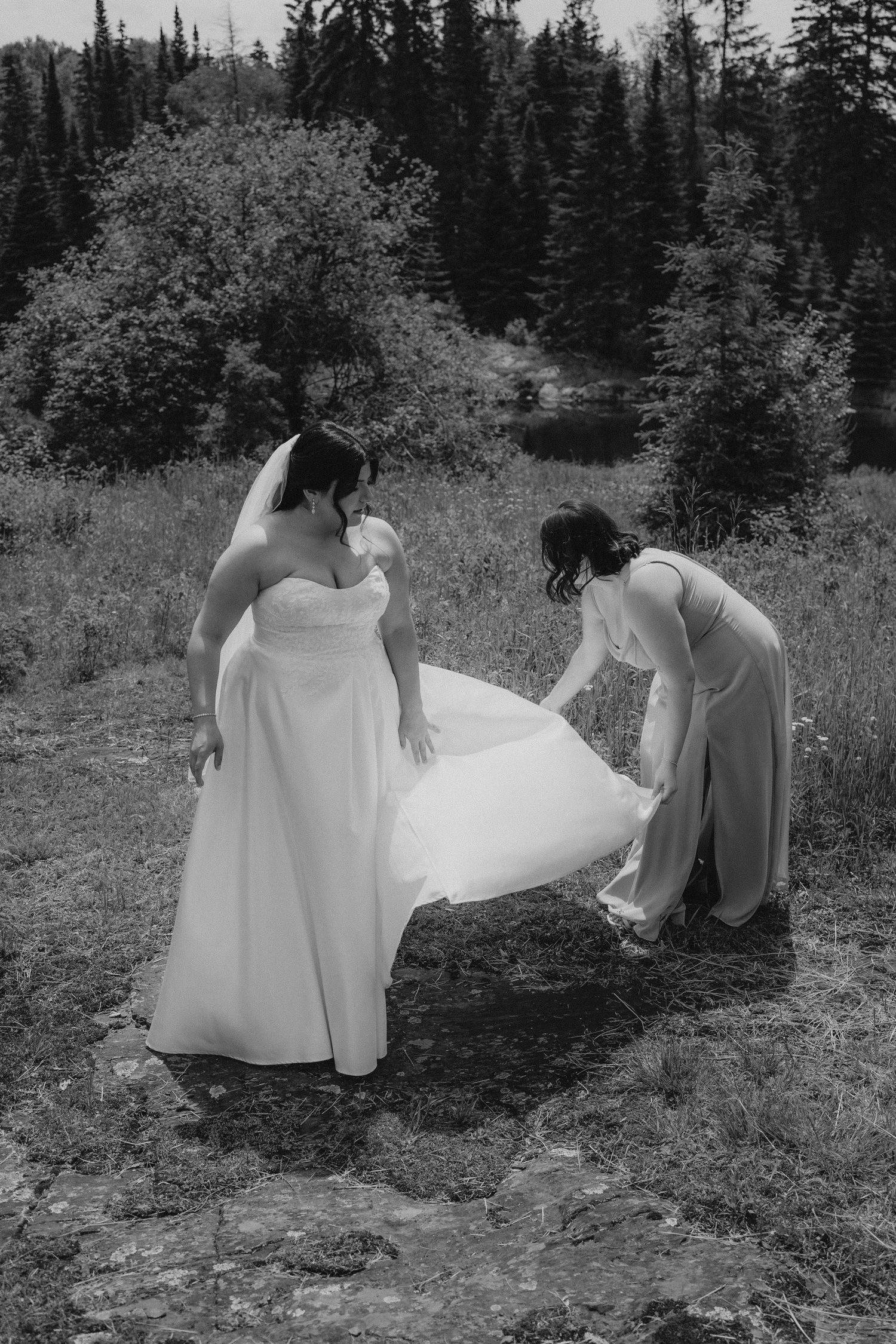 Wedding dress being adjusted outdoors in a scenic mountain setting.
