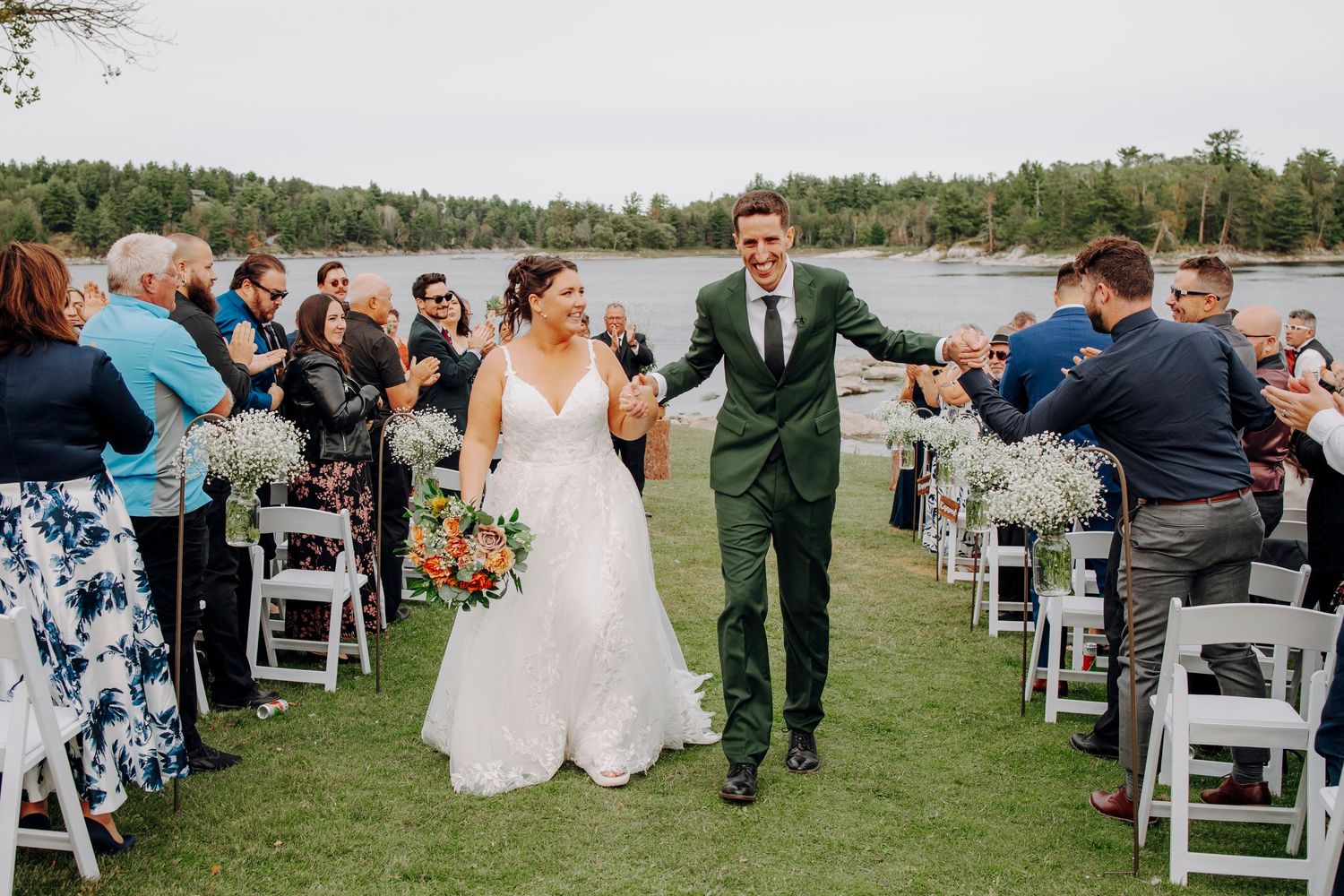 Outdoor wedding reception by the water with rows of white chairs and scenic views.