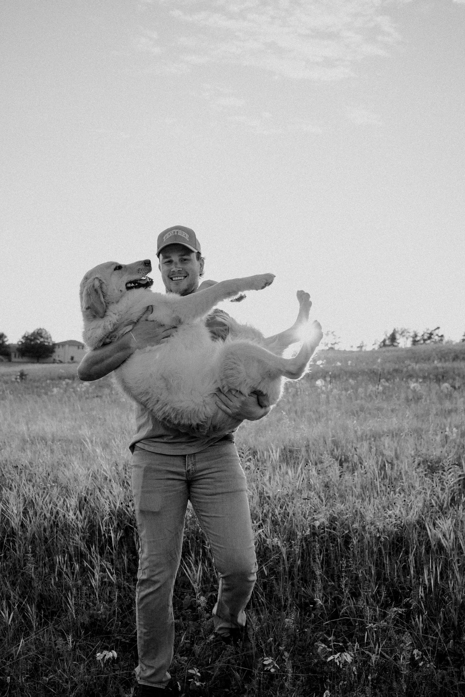 Someone holding a playful golden retriever in their arms outdoors.