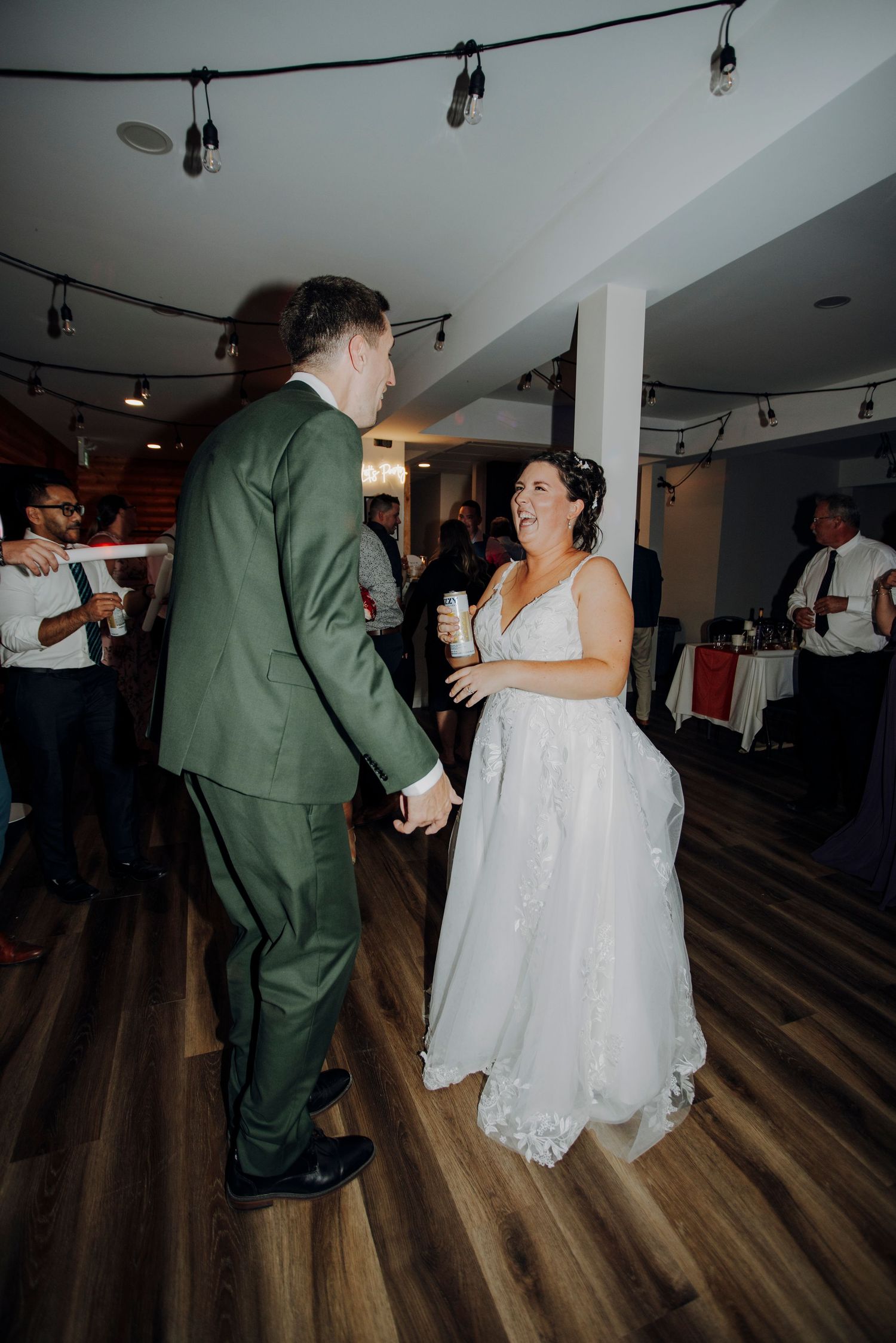 A couple shares their first dance at a wedding reception on a dark hardwood floor.