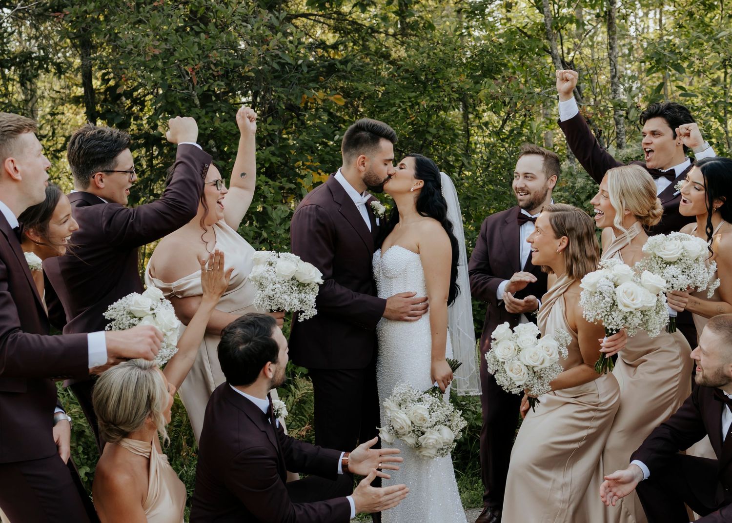 Wedding party celebrating with champagne outdoors in formal attire.