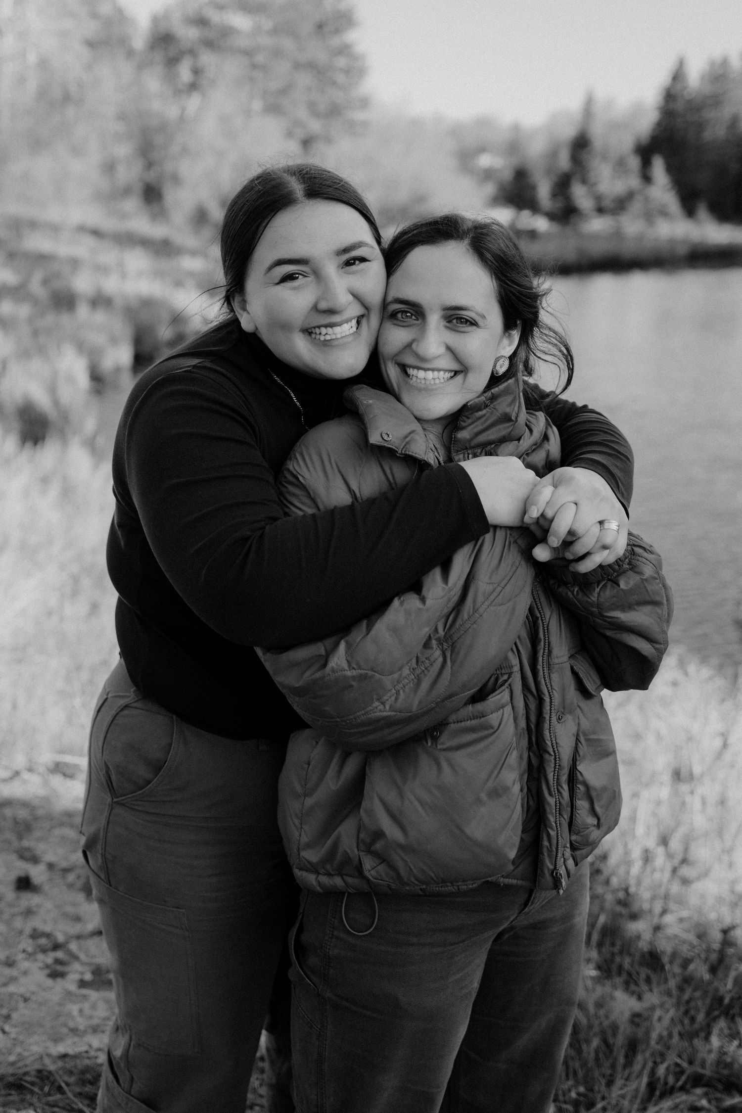 A series of candid black and white photos showing two people embracing and laughing together outdoors in nature.