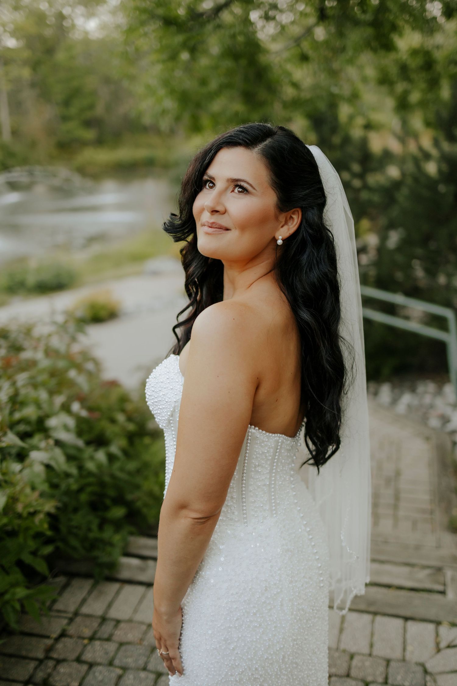 A bride in a beaded white wedding dress poses outdoors in a series of portrait shots.