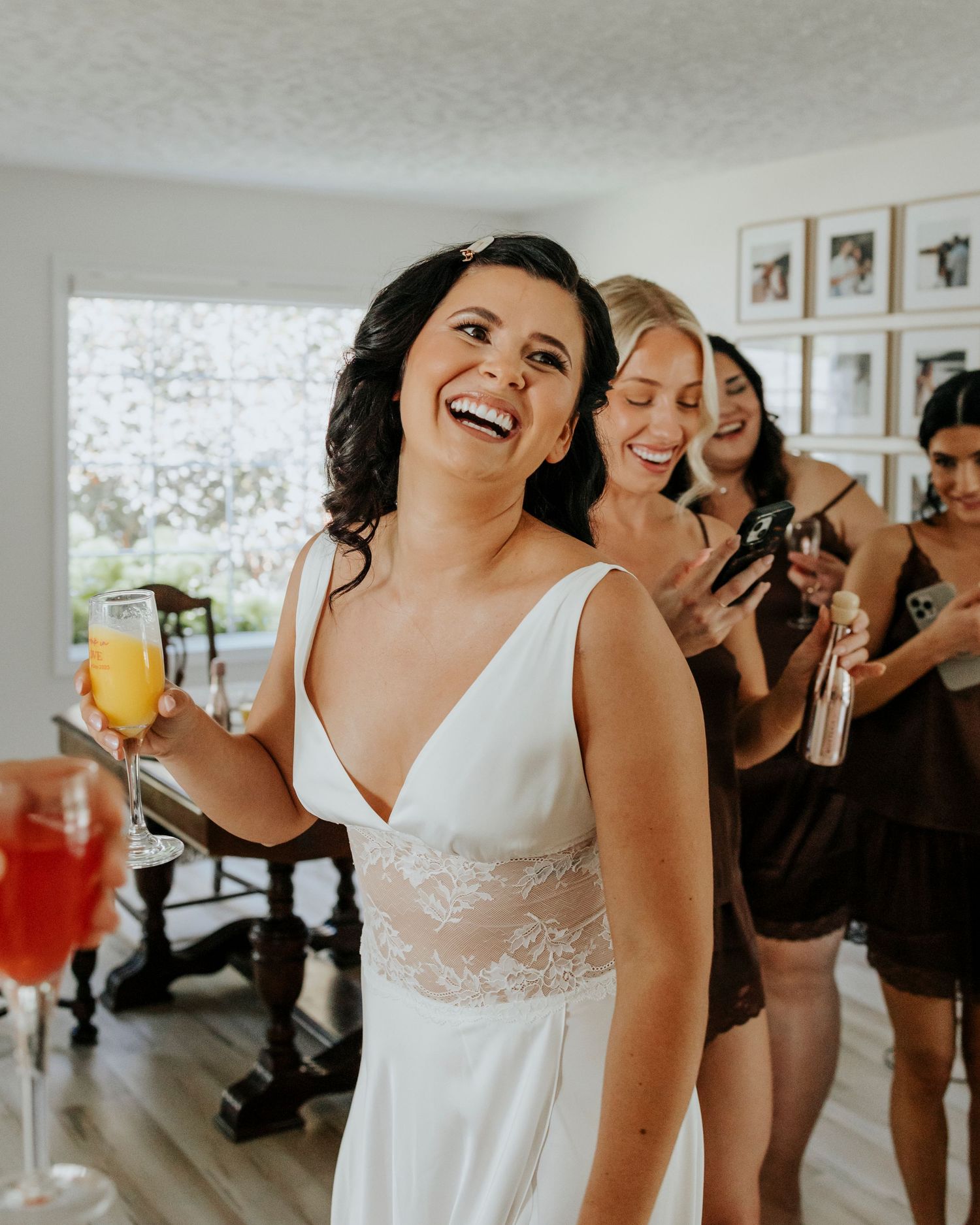 Wedding party members in white and black attire share joyful laughter during pre-ceremony preparations.