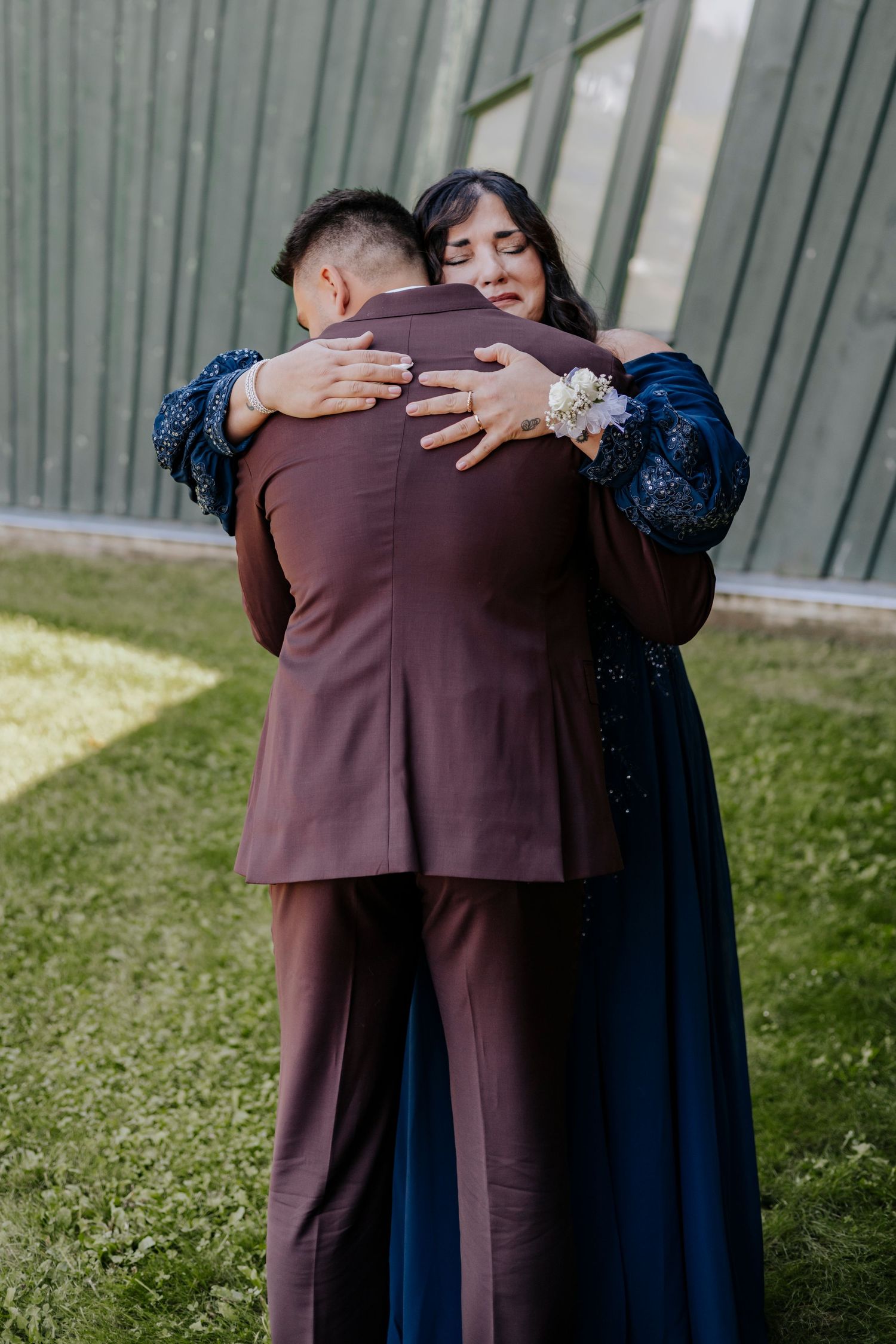 Wedding couple embracing outdoors, with the bride wearing a navy blue dress.