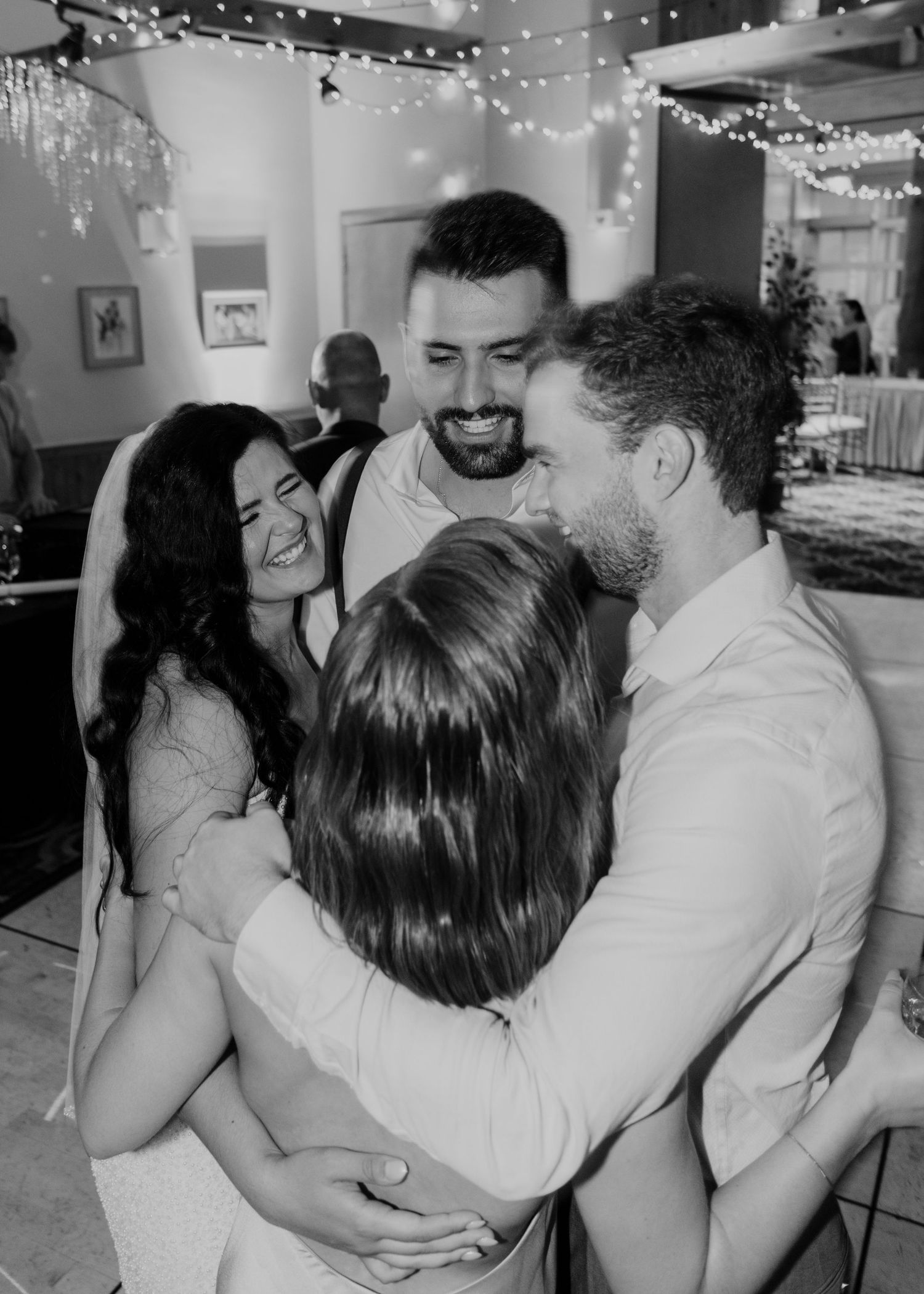 A sequence of candid reception photos showing wedding guests dancing and embracing under string lights indoors.