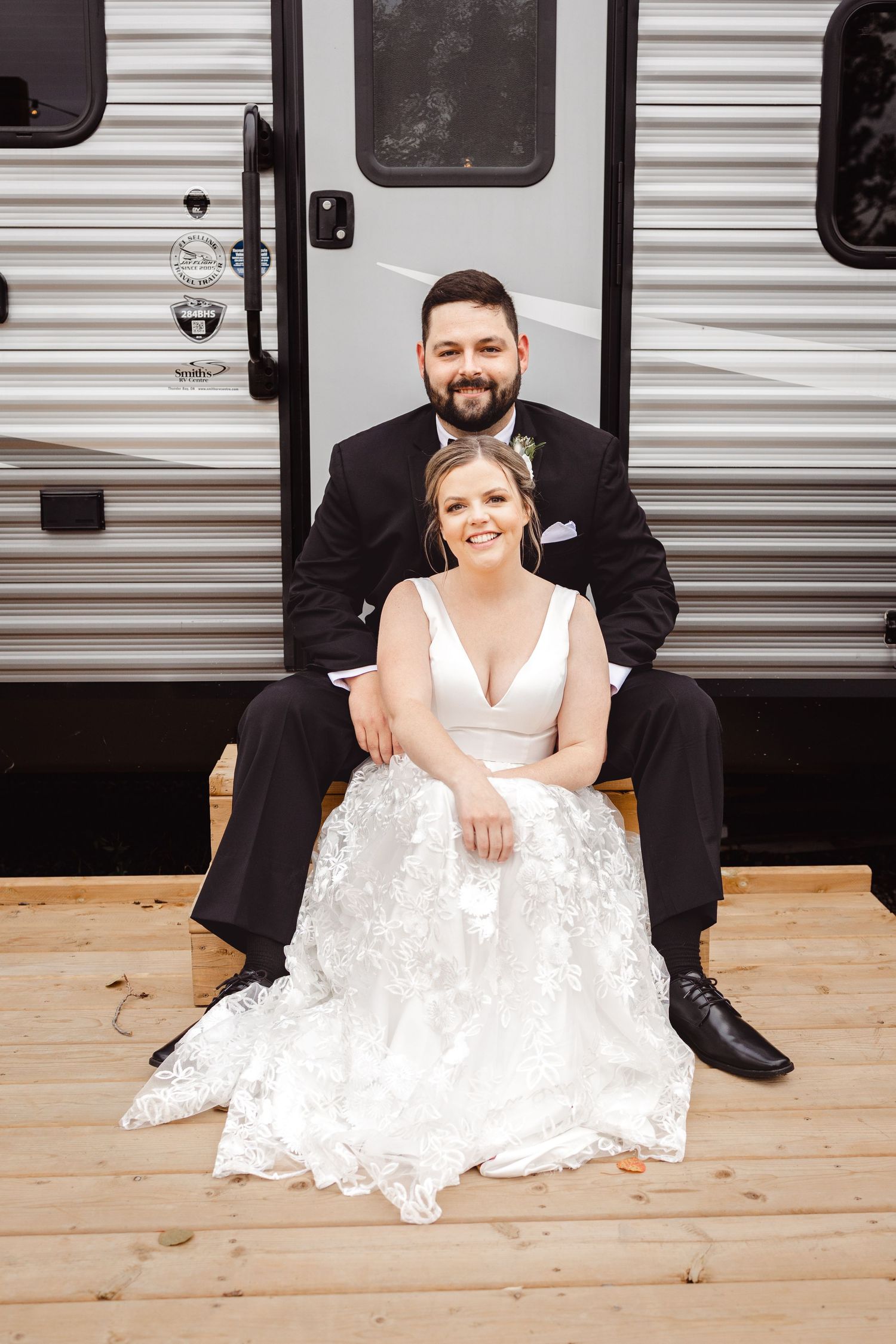 Wedding couple posing casually in front of a travel trailer.