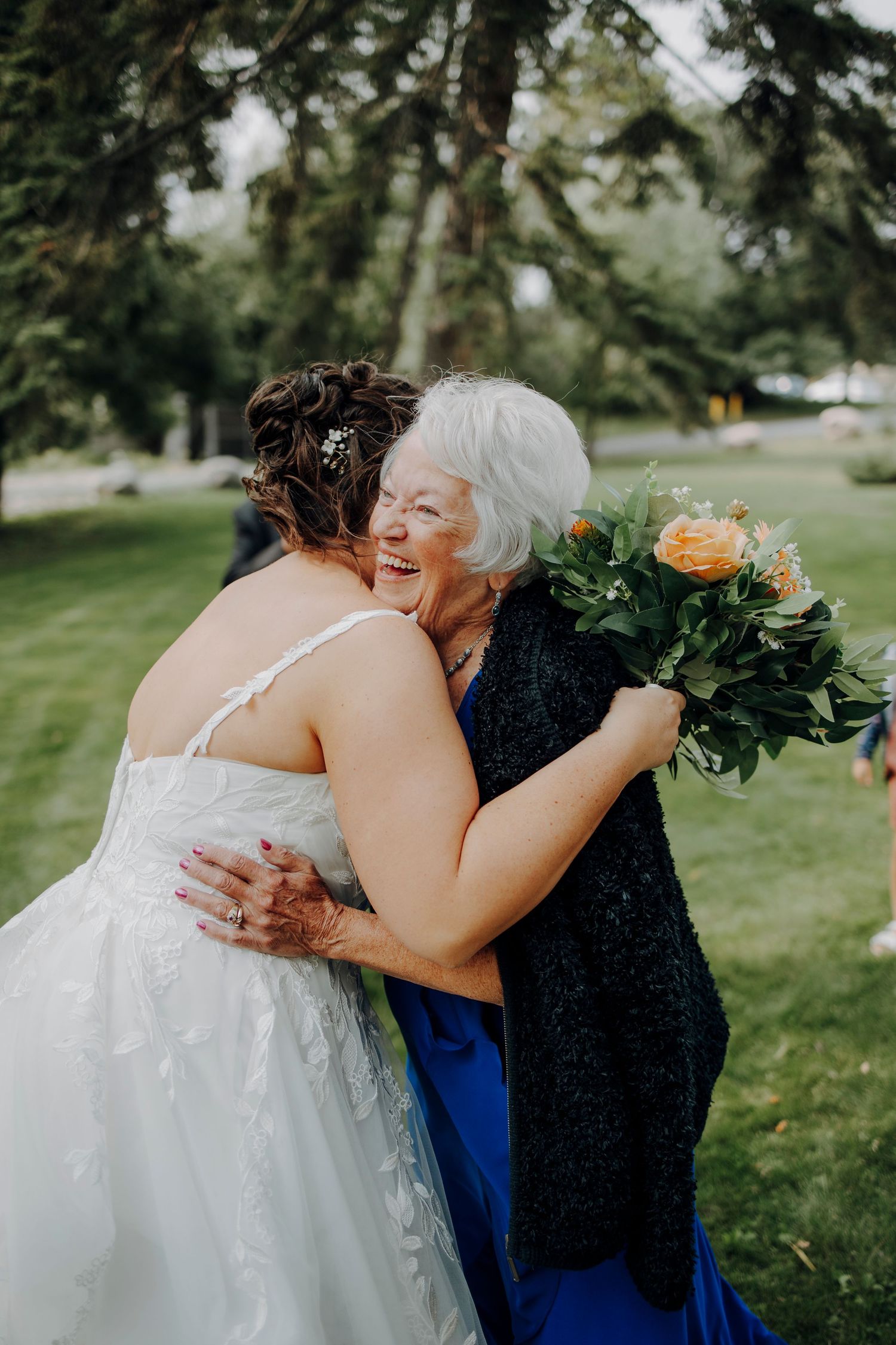 Emotional embrace between wedding guests during outdoor celebration.
