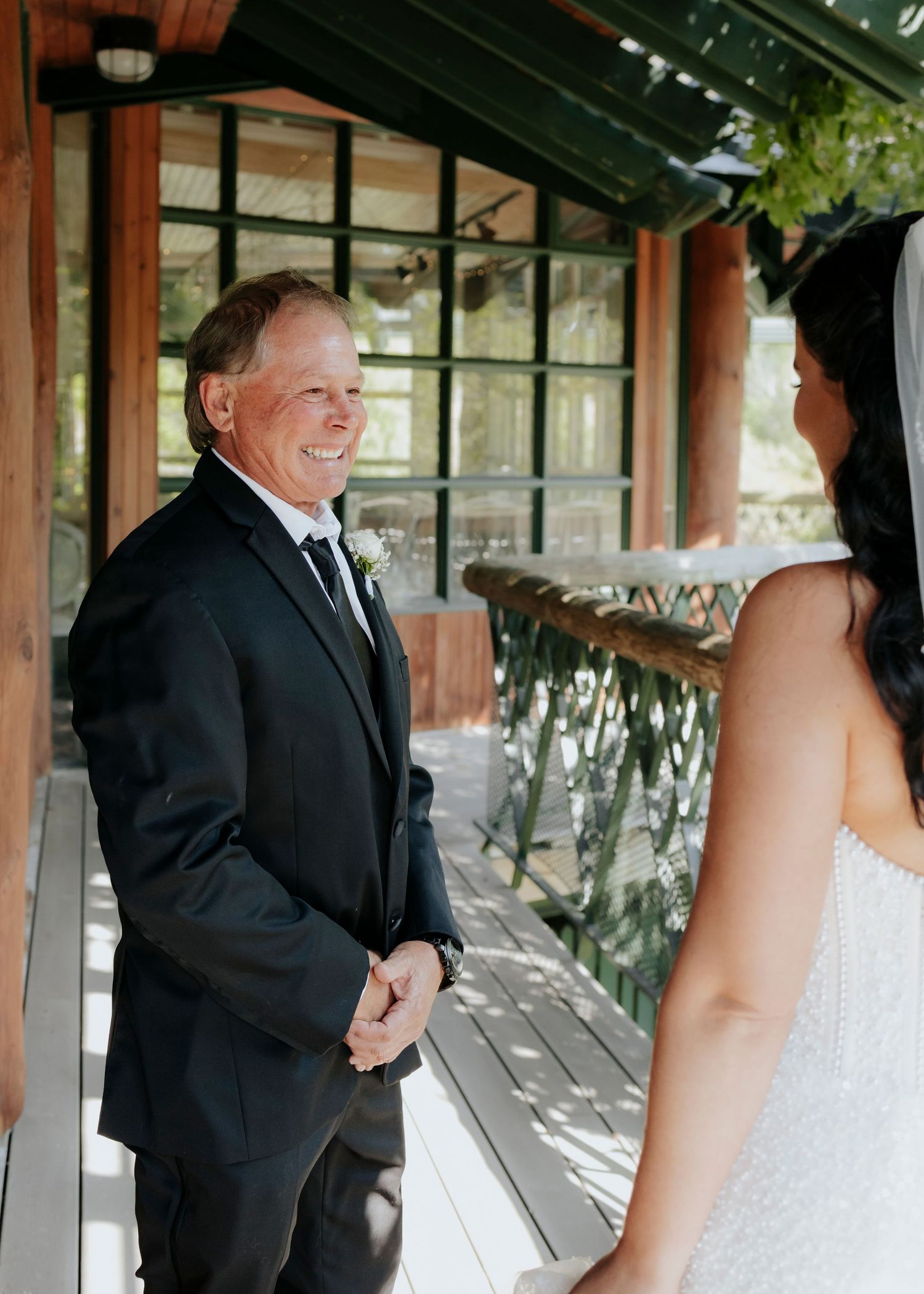 Joyful reactions during a wedding first look under a rustic wooden pavilion.