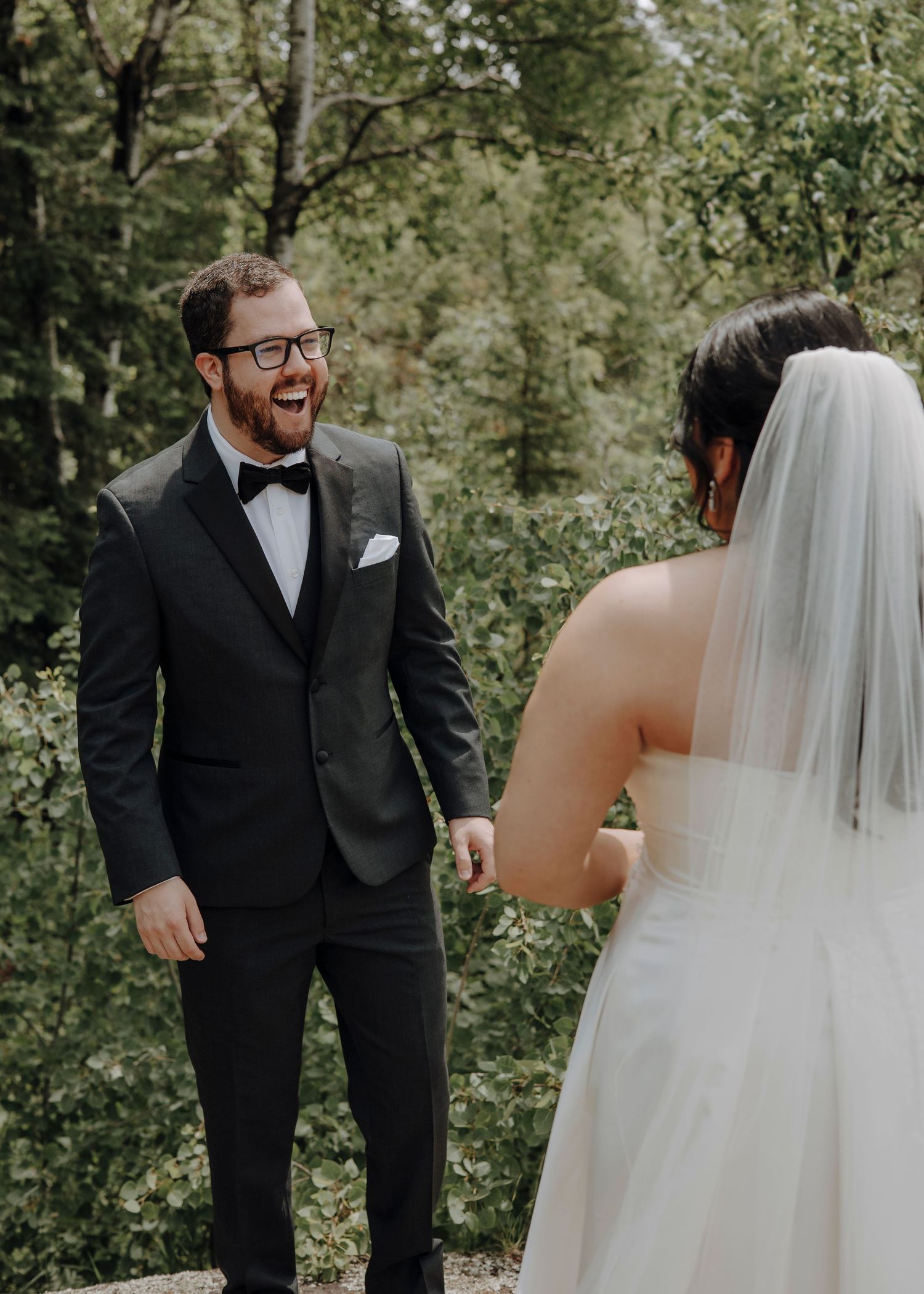 A wedding first look moment captured in a lush green forest setting.