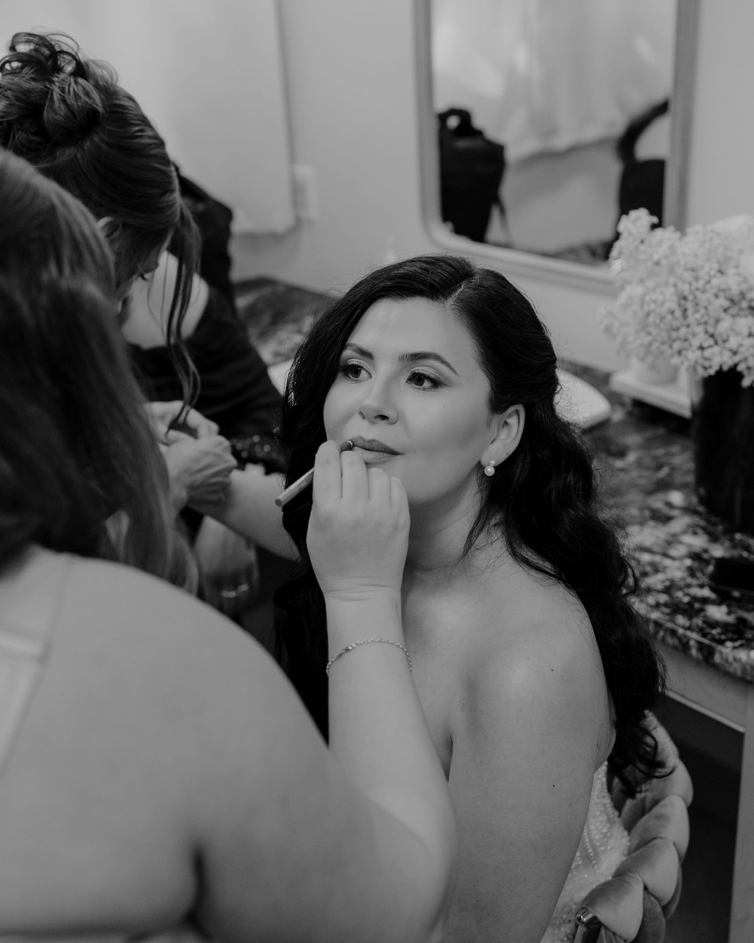 A series of black and white photos showing makeup being applied during wedding preparations.
