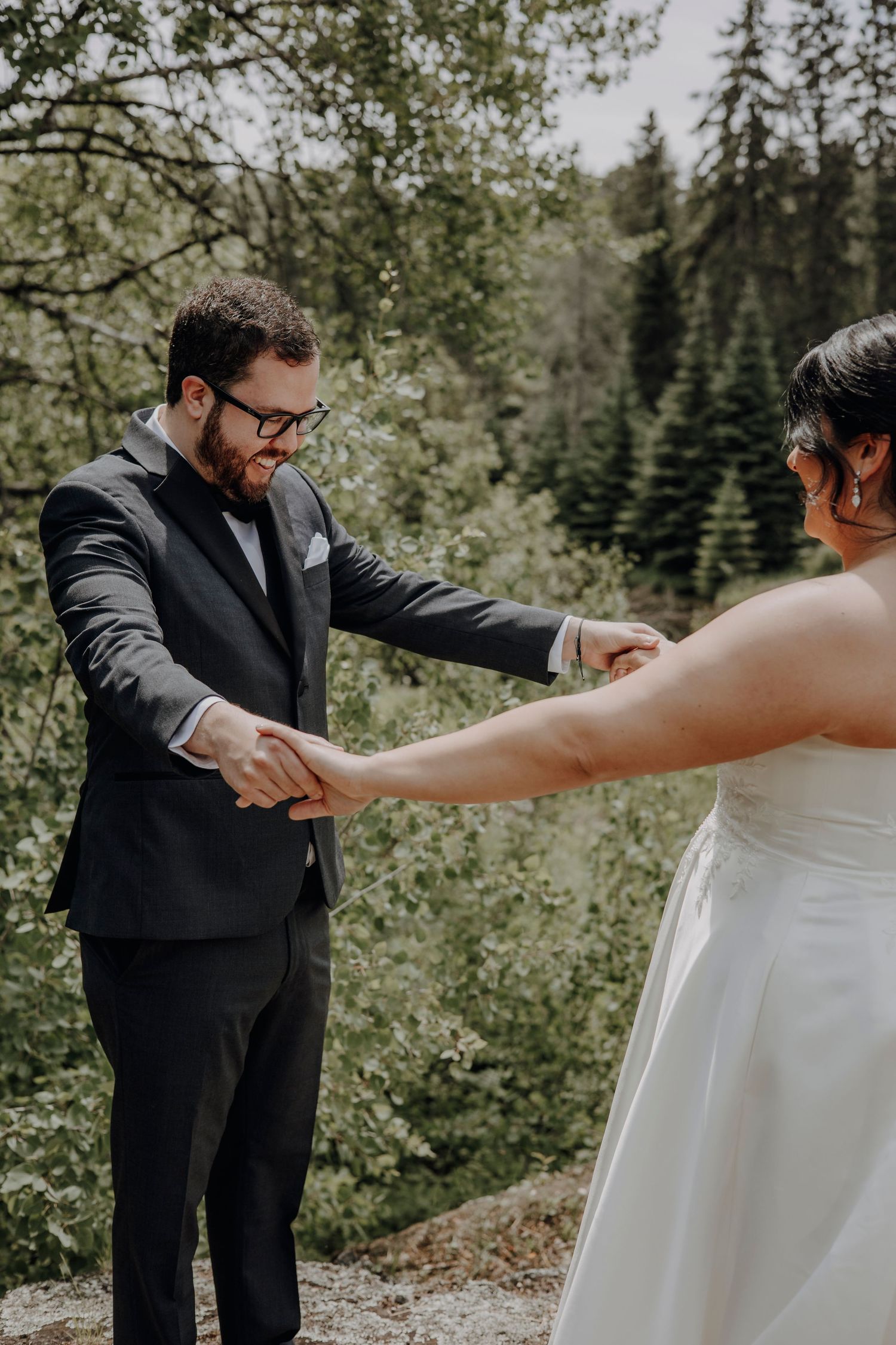 A couple shares a romantic first look moment in a scenic forest setting during their wedding day.