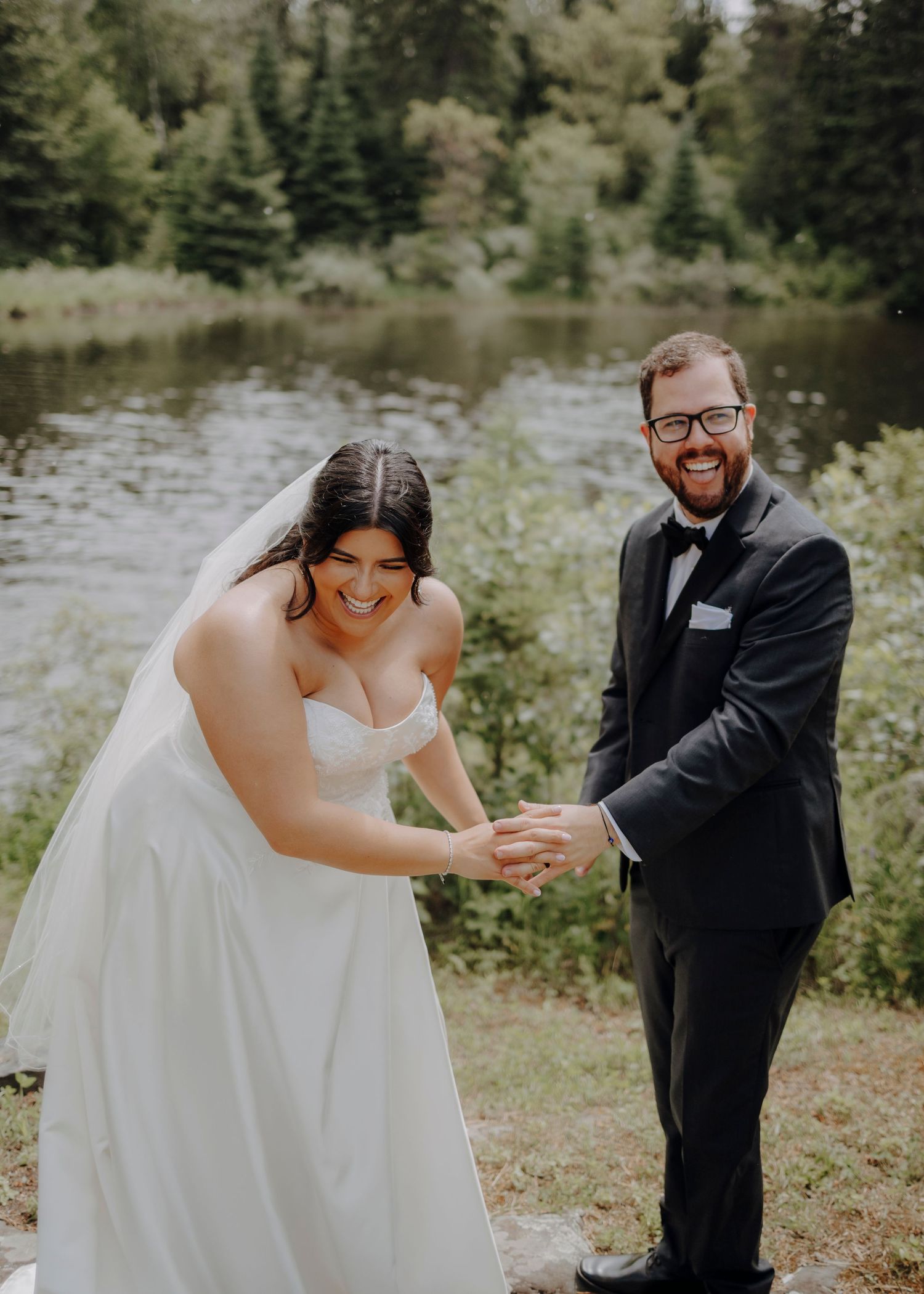 Playful wedding couple shares candid moments on a gravel path surrounded by lush greenery.