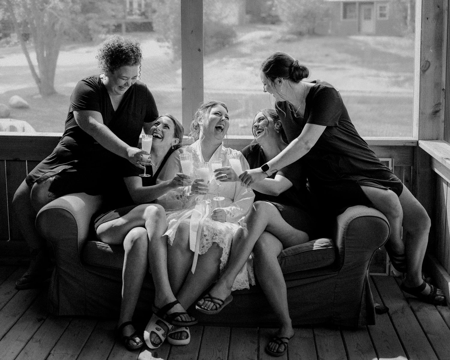 Group of people relaxing and socializing on a covered porch with casual seating.