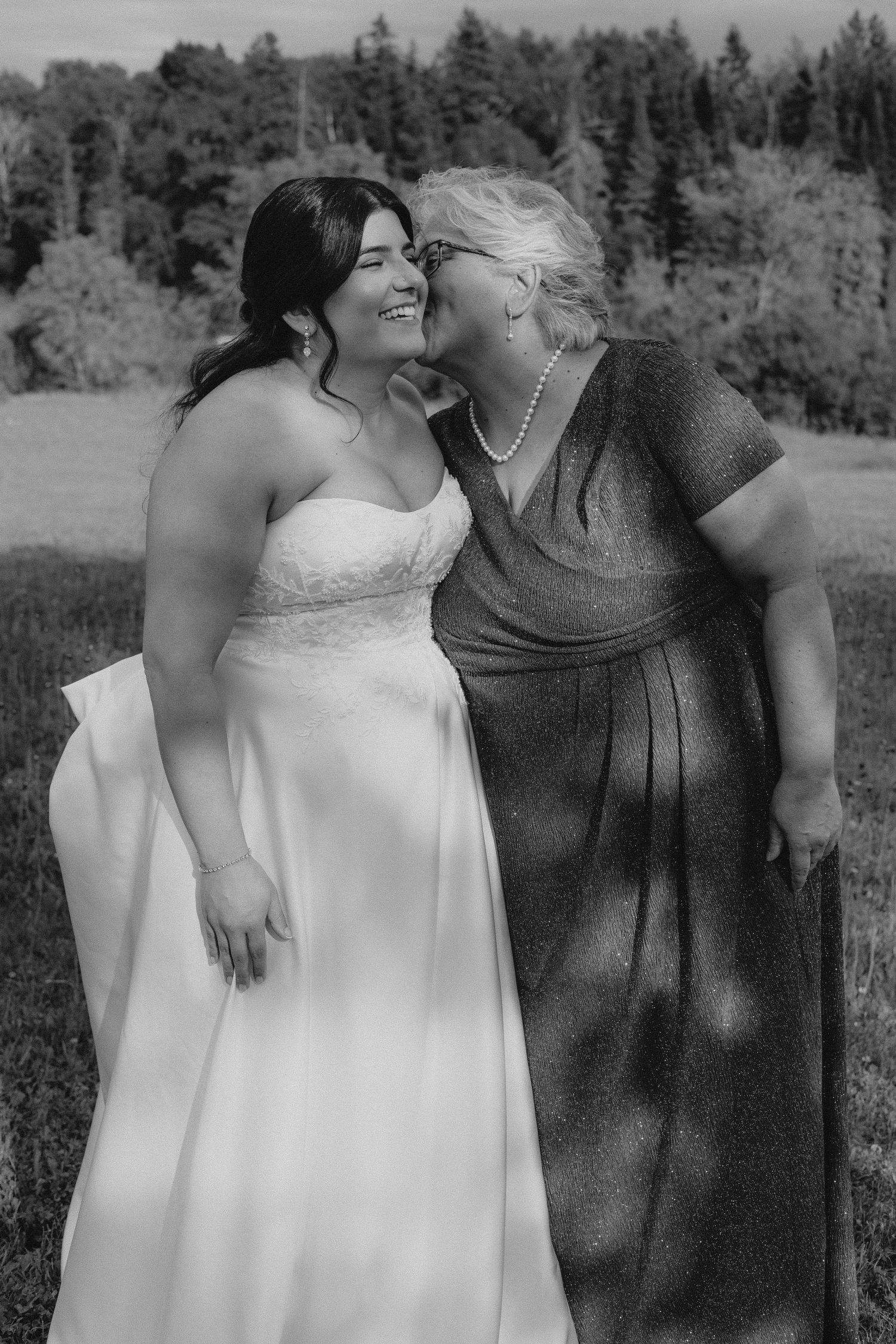 A couple in wedding attire embraces in a scenic forest setting.
