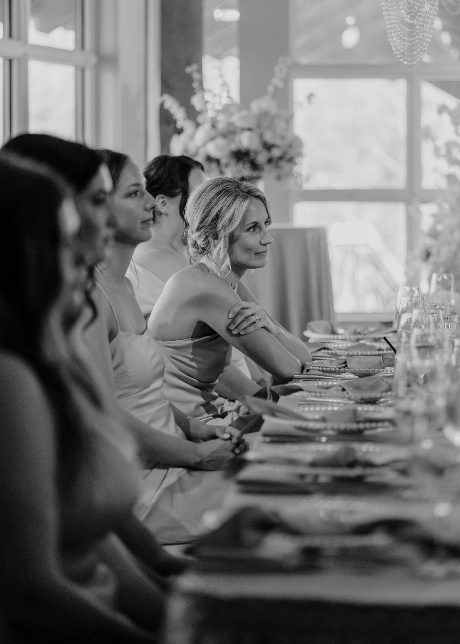 Black and white photo of wedding reception dinner with guests seated at long tables.