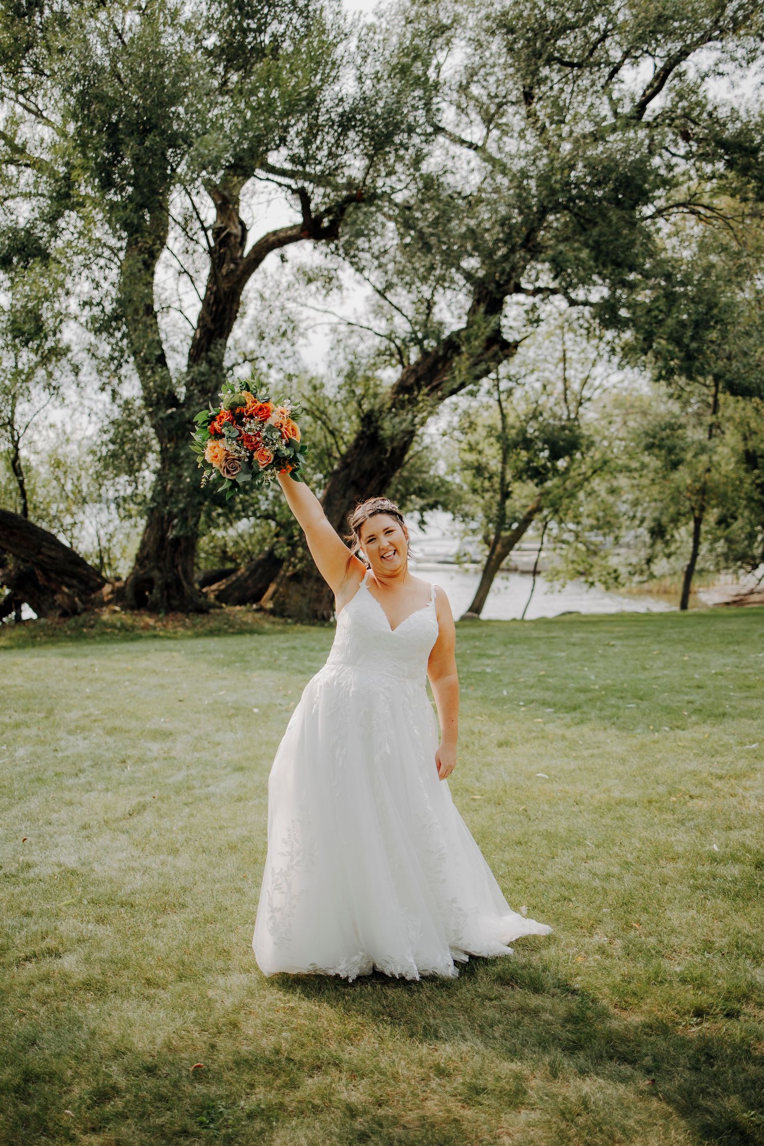 Bride in flowing white dress twirling in outdoor garden setting.