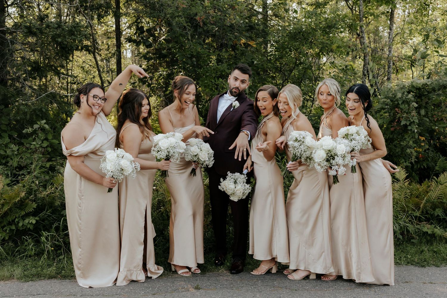 Bridesmaids in champagne-colored dresses pose together outdoors for wedding photos.