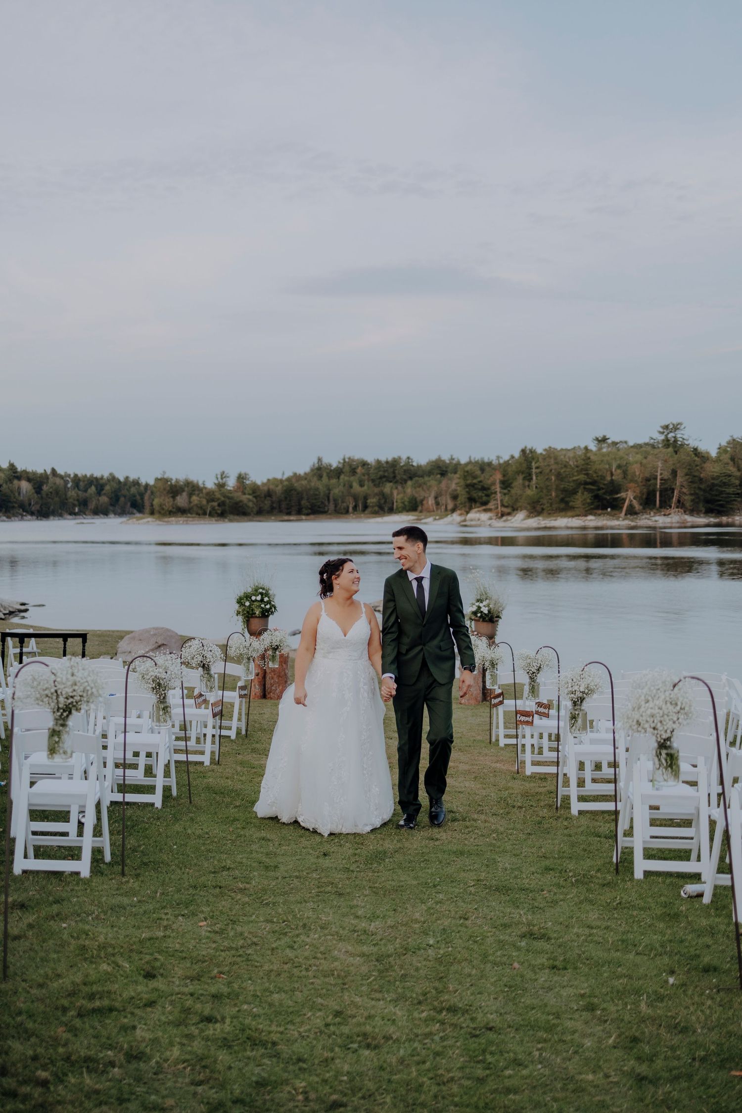 Lakeside wedding ceremony setup with white chairs and water views.