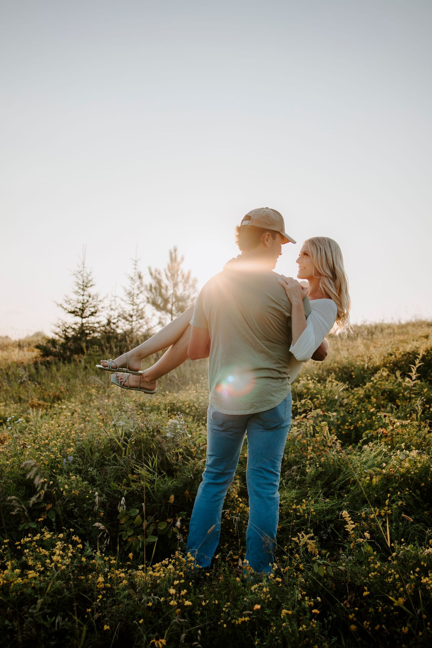 A romantic sunset scene with someone being carried in a wildflower field.