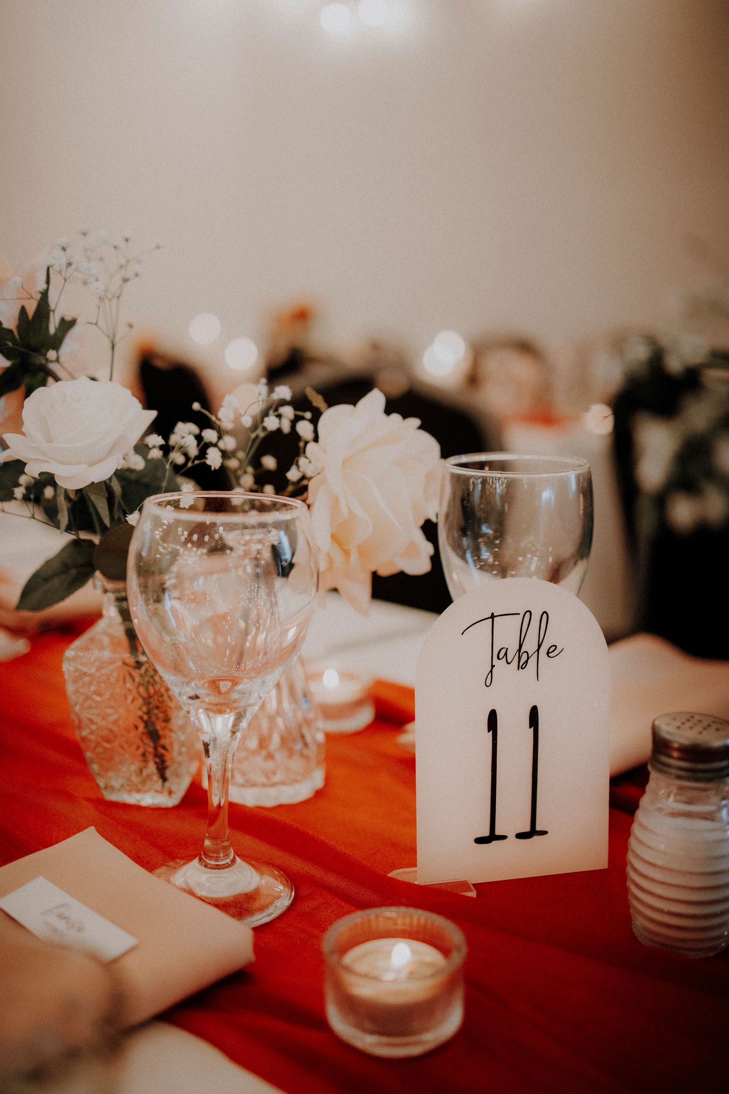 Elegant wedding reception table setting with crystal glasses and table number eleven.