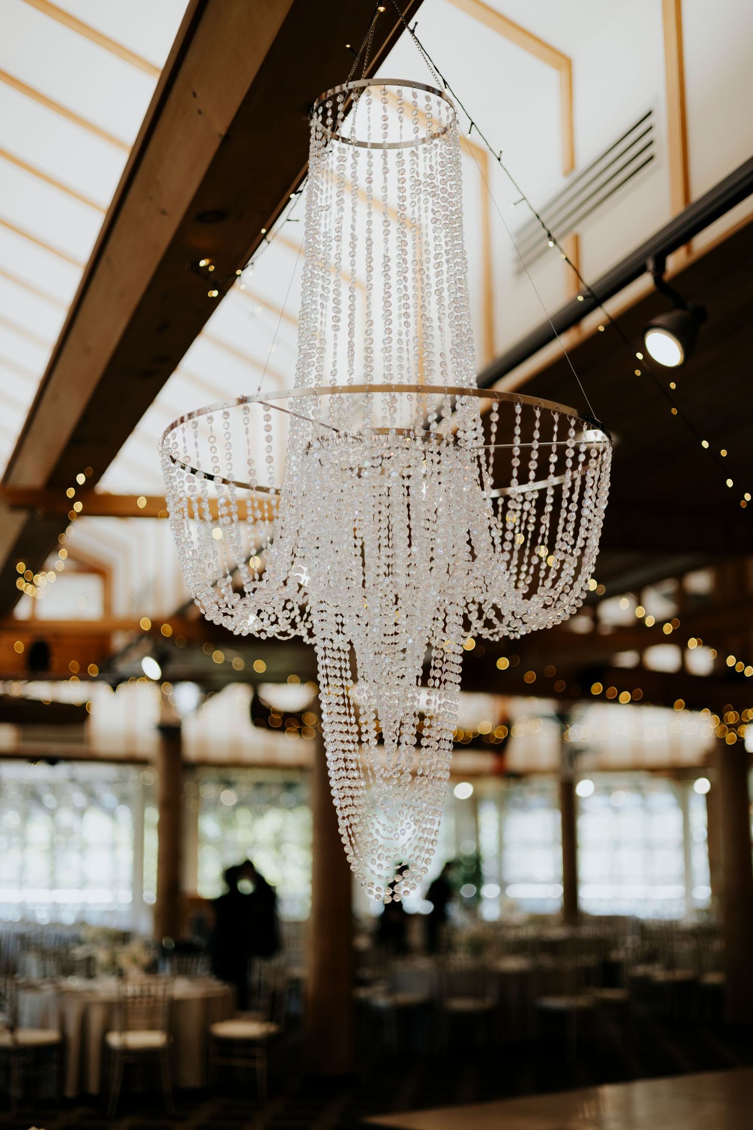 Crystal chandeliers hang elegantly in a wedding venue, creating a luxurious atmosphere.
