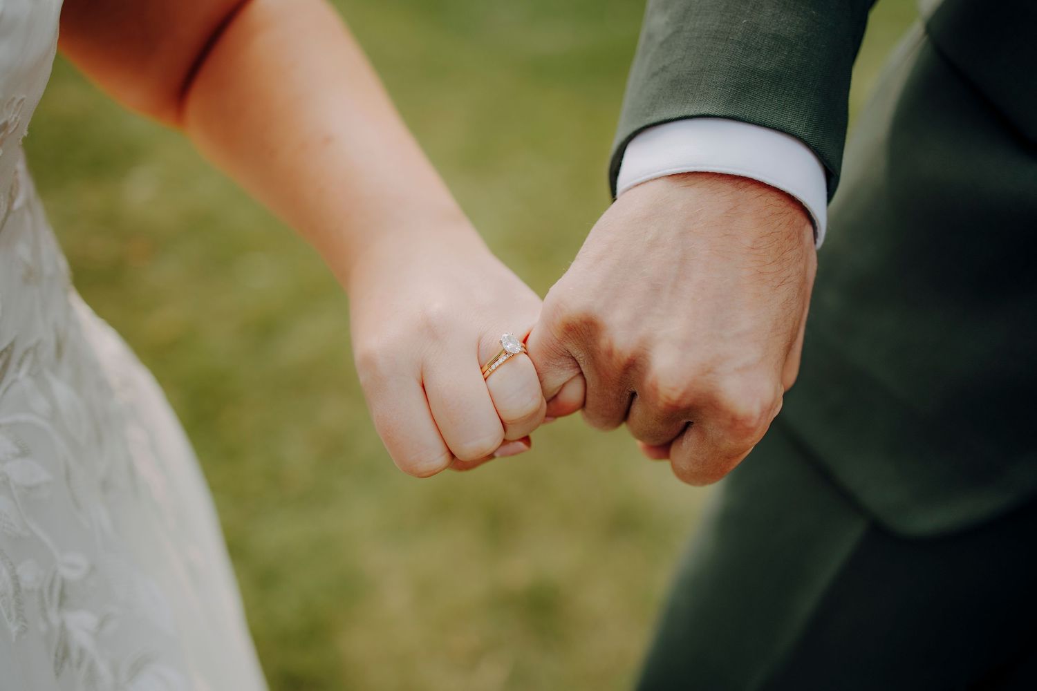 Close-up of couple holding hands during outdoor wedding ceremony.