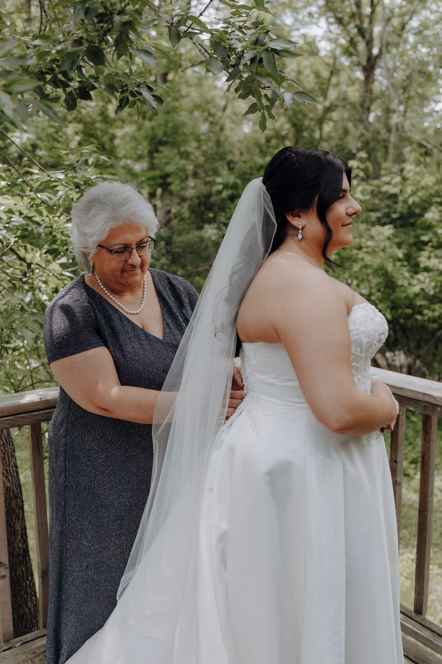 A touching moment during a wedding as family members help with the bride's dress and veil.