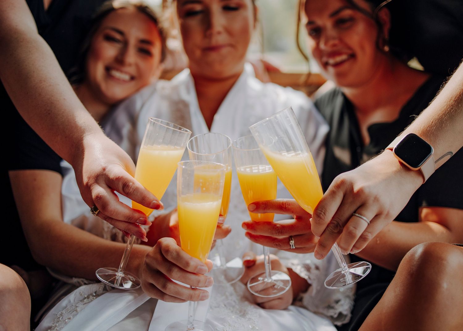 A group toasts with mimosa cocktails in champagne glasses during a celebratory gathering.