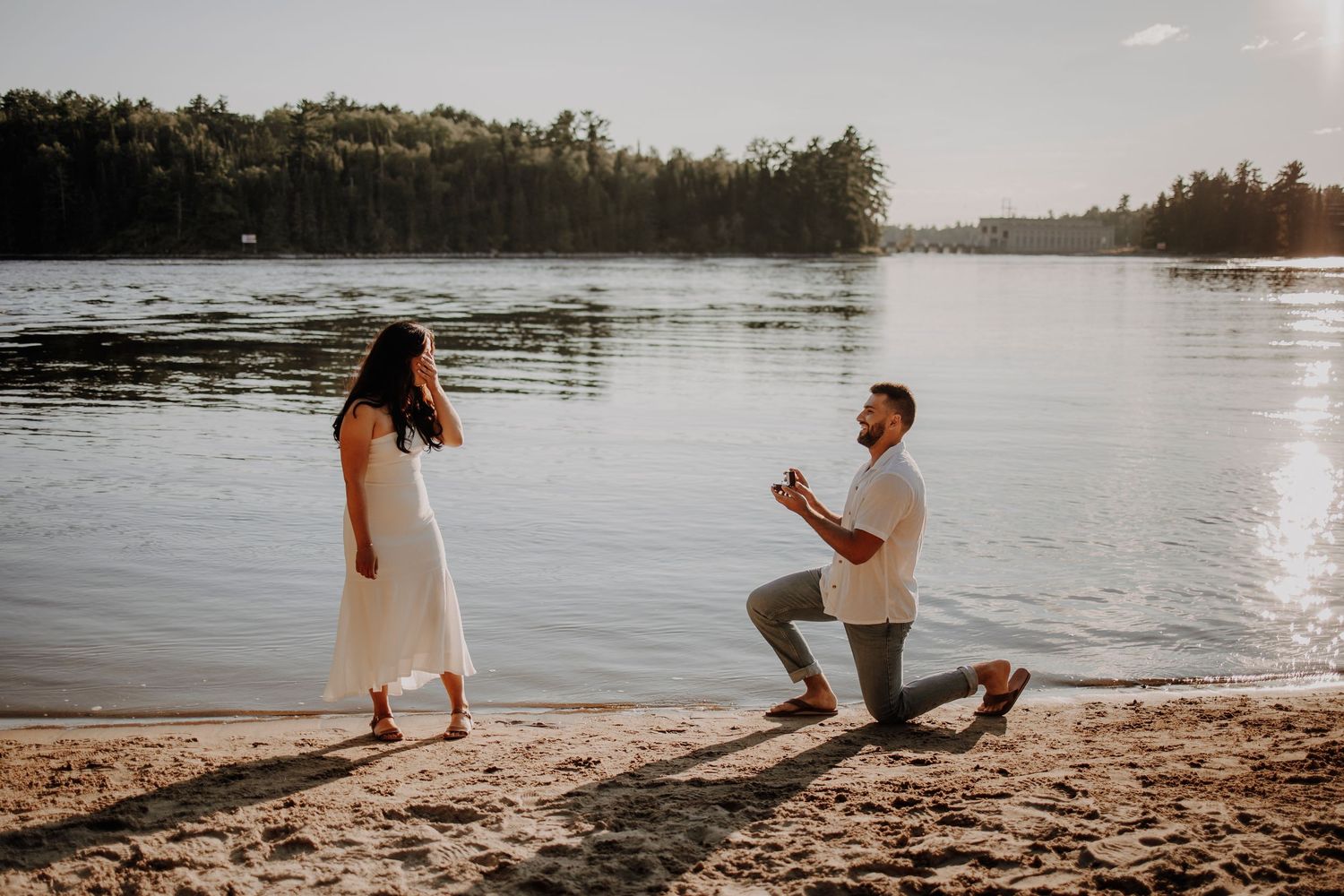 A romantic beach proposal scene during sunset by the lake.