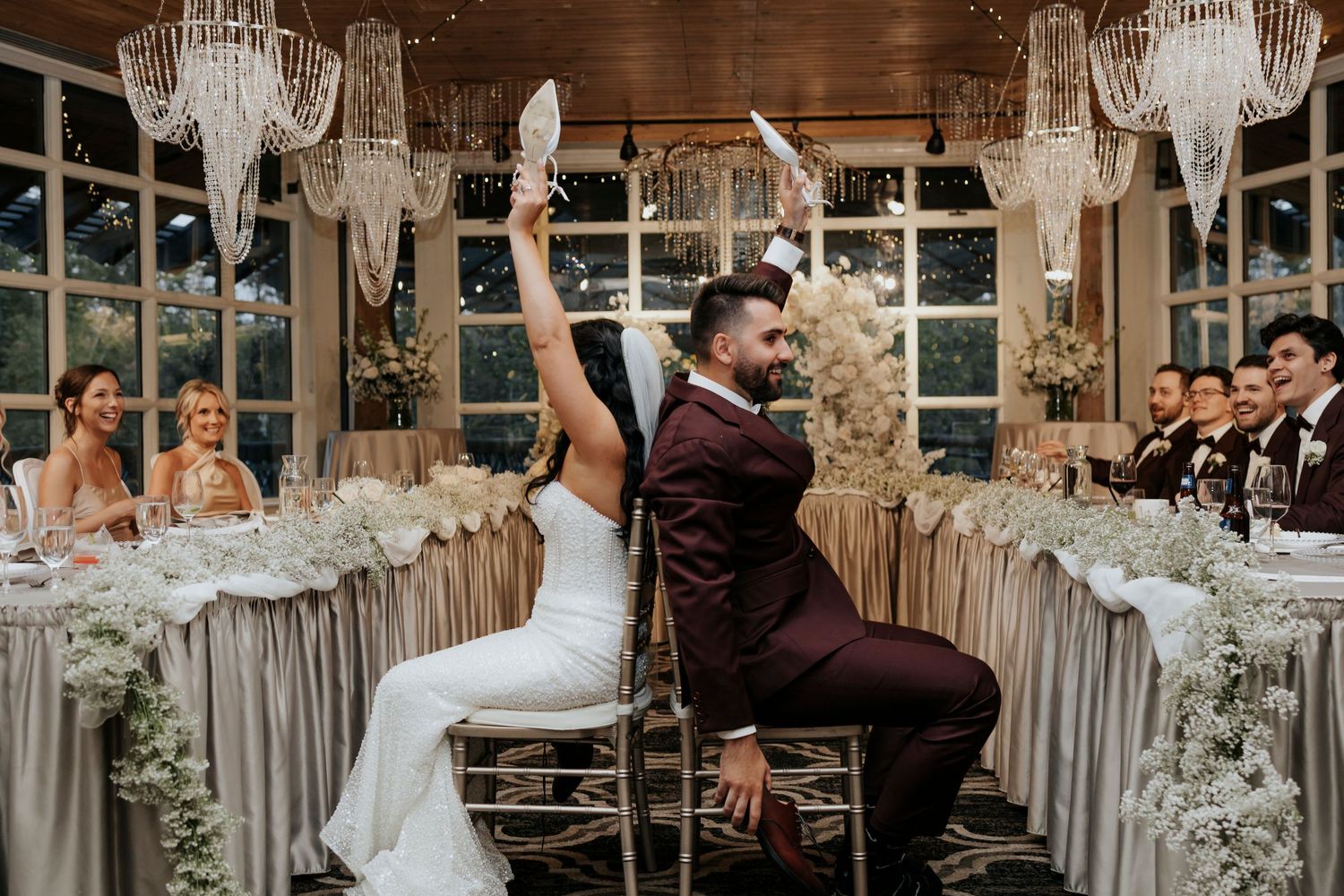 An elegant wedding reception venue decorated with crystal chandeliers and white floral arrangements.