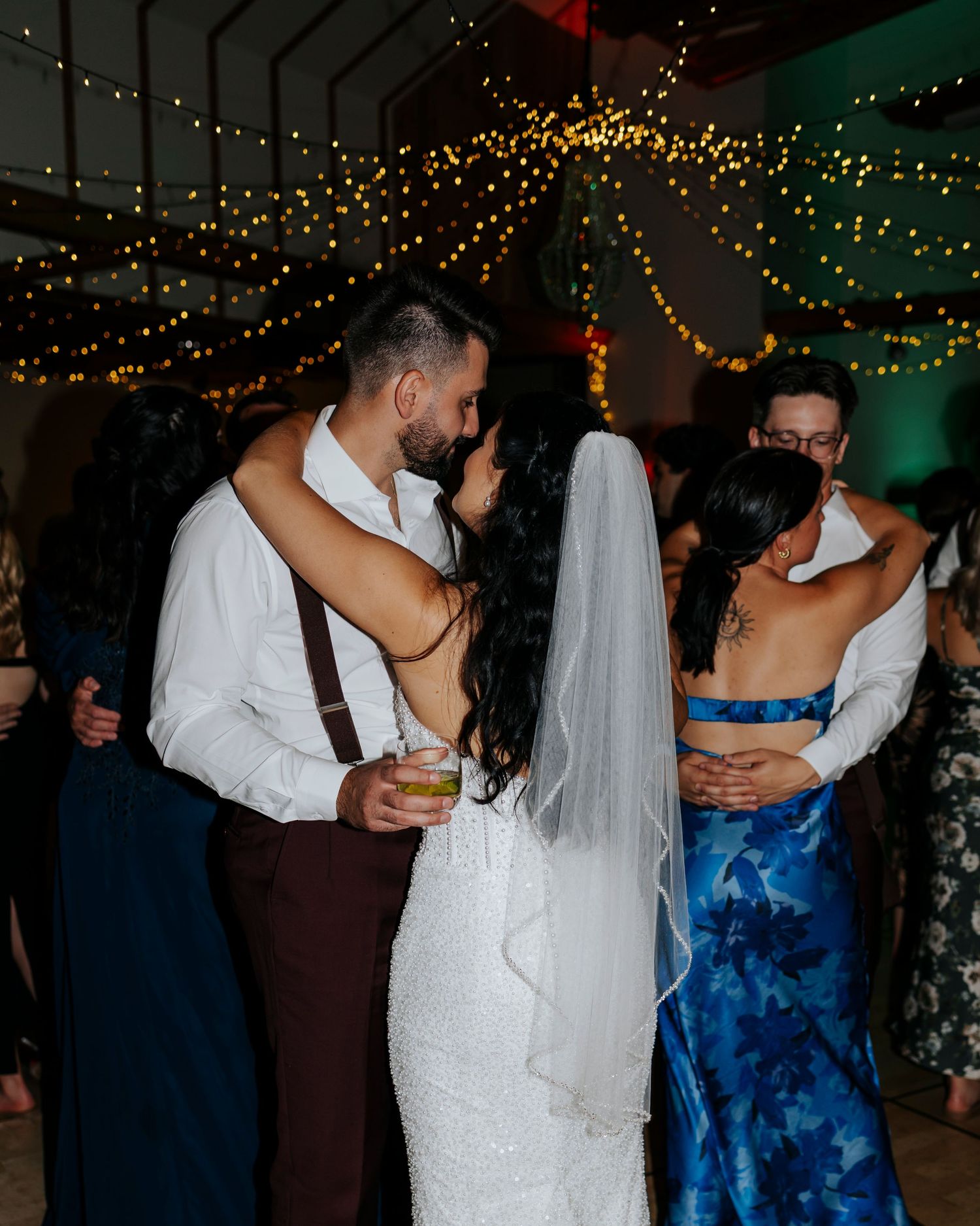 Wedding reception dance floor with string lights and guests in formal attire.