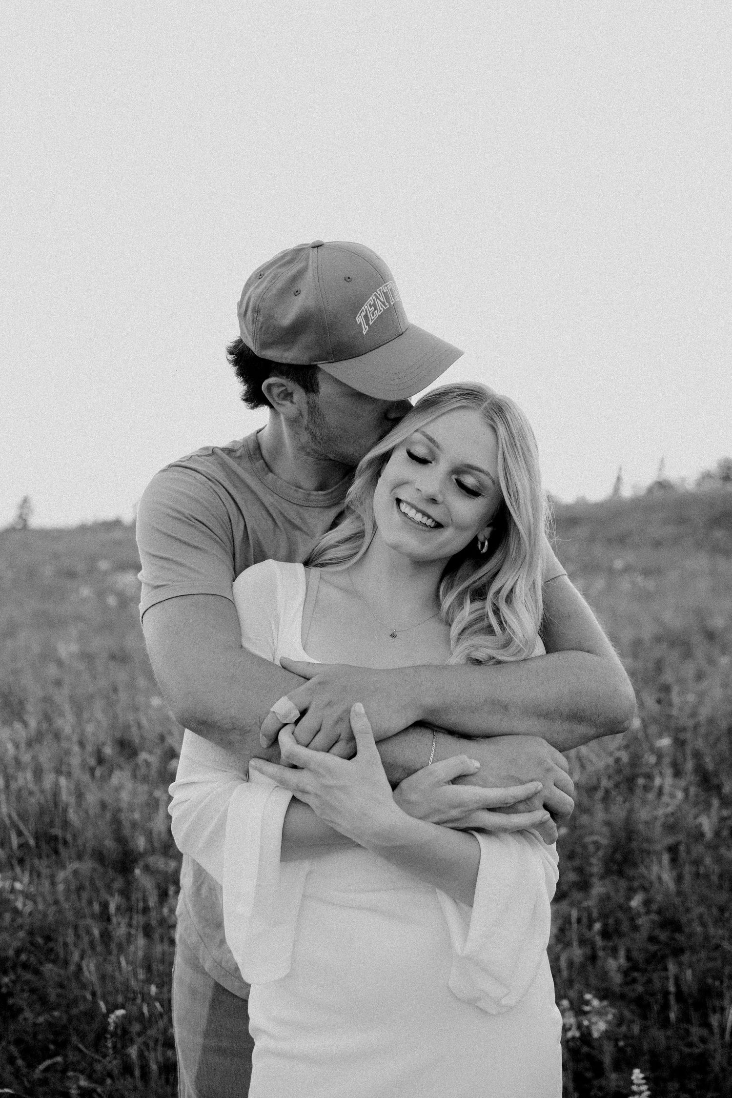 Couple embracing in black and white portrait in a sunny field.