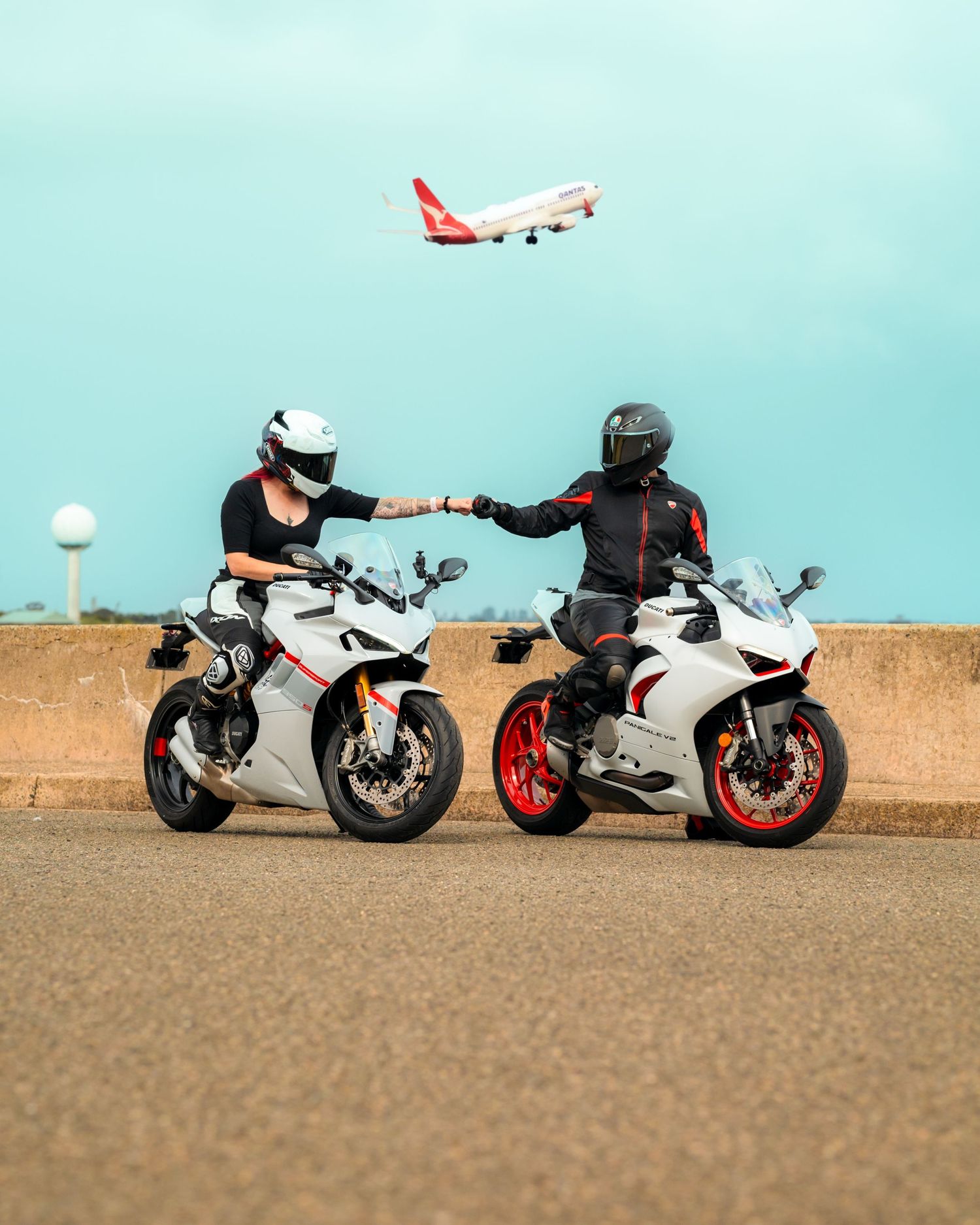 Two people on motorcycles with a plane in the background
