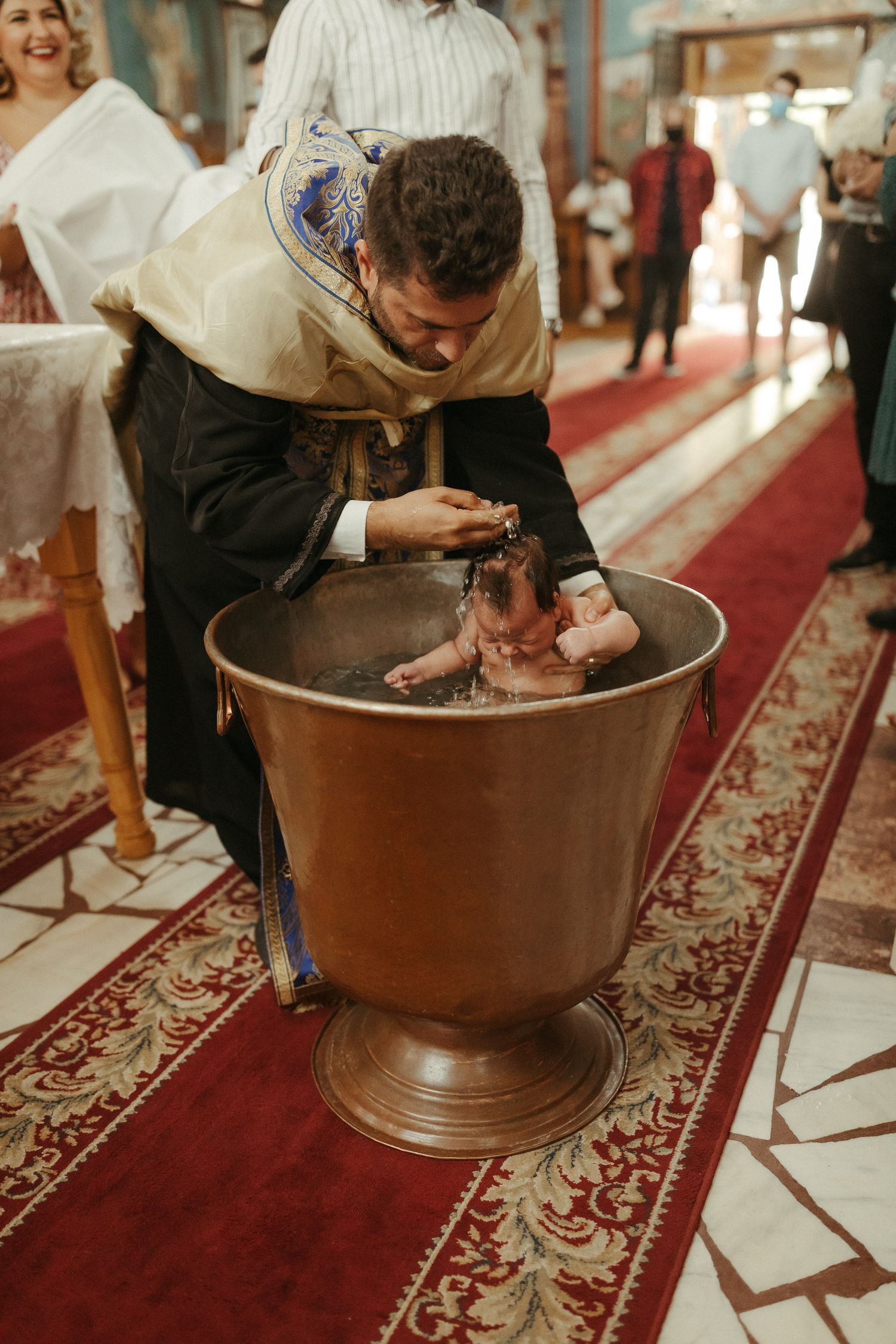 copil in cristelnita fiind botezat de preot in biserica