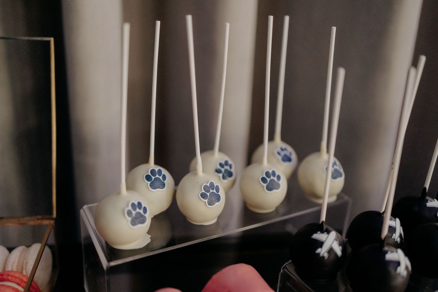 Cake pops delicioase decorate cu lăbuțe de cățel și avioane; detalii personalizate și creative de pe masa de dulciuri de la nuntă.