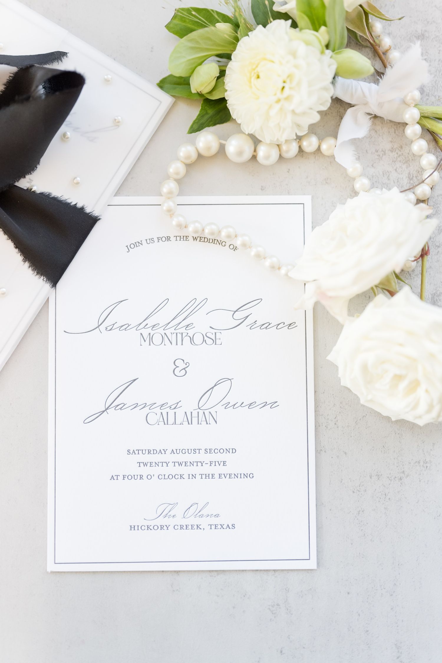 Elegant wedding invitations and place cards in classic calligraphy with white flowers and pearl decorations.