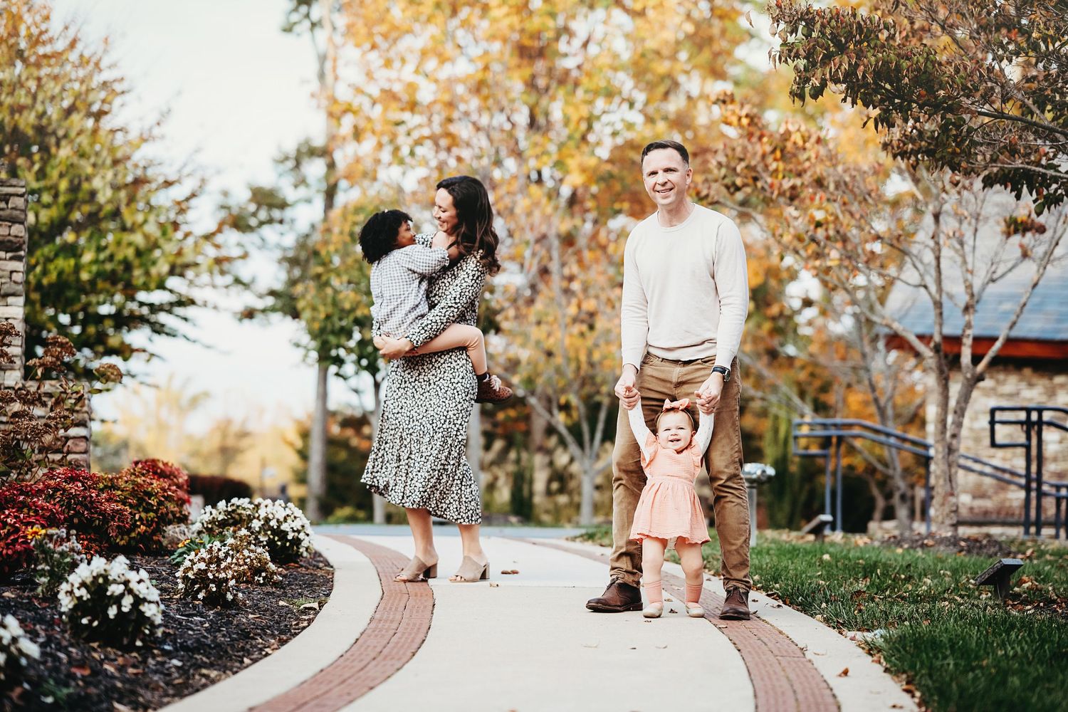 Family photoshoot in a park setting during autumn with golden sunlight.