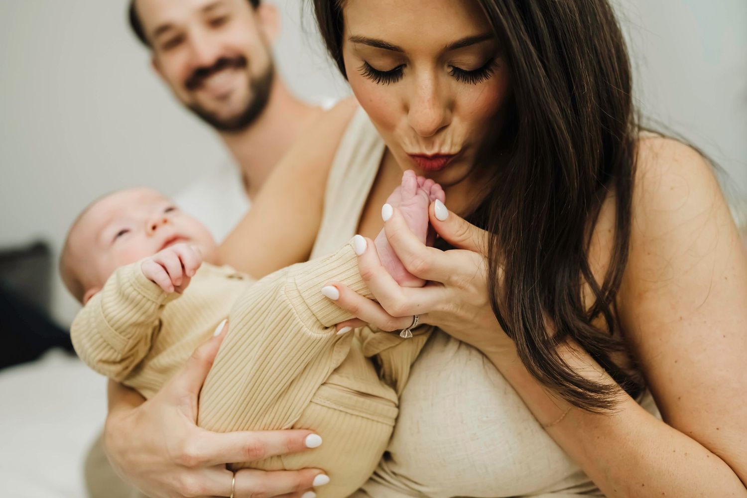 Parents tenderly bond with their newborn baby dressed in a beige outfit.
