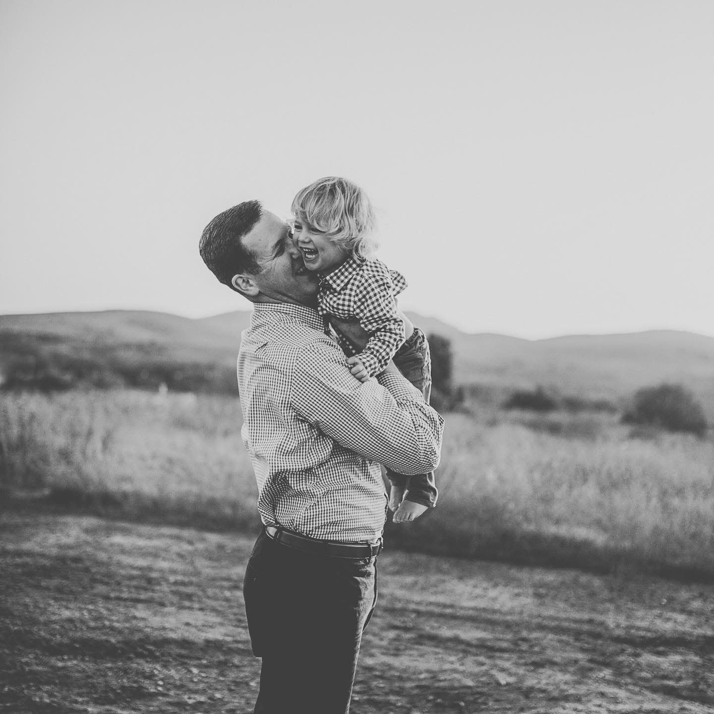 Black and white portrait series showing tender moments in an outdoor setting. Father and son giggles.