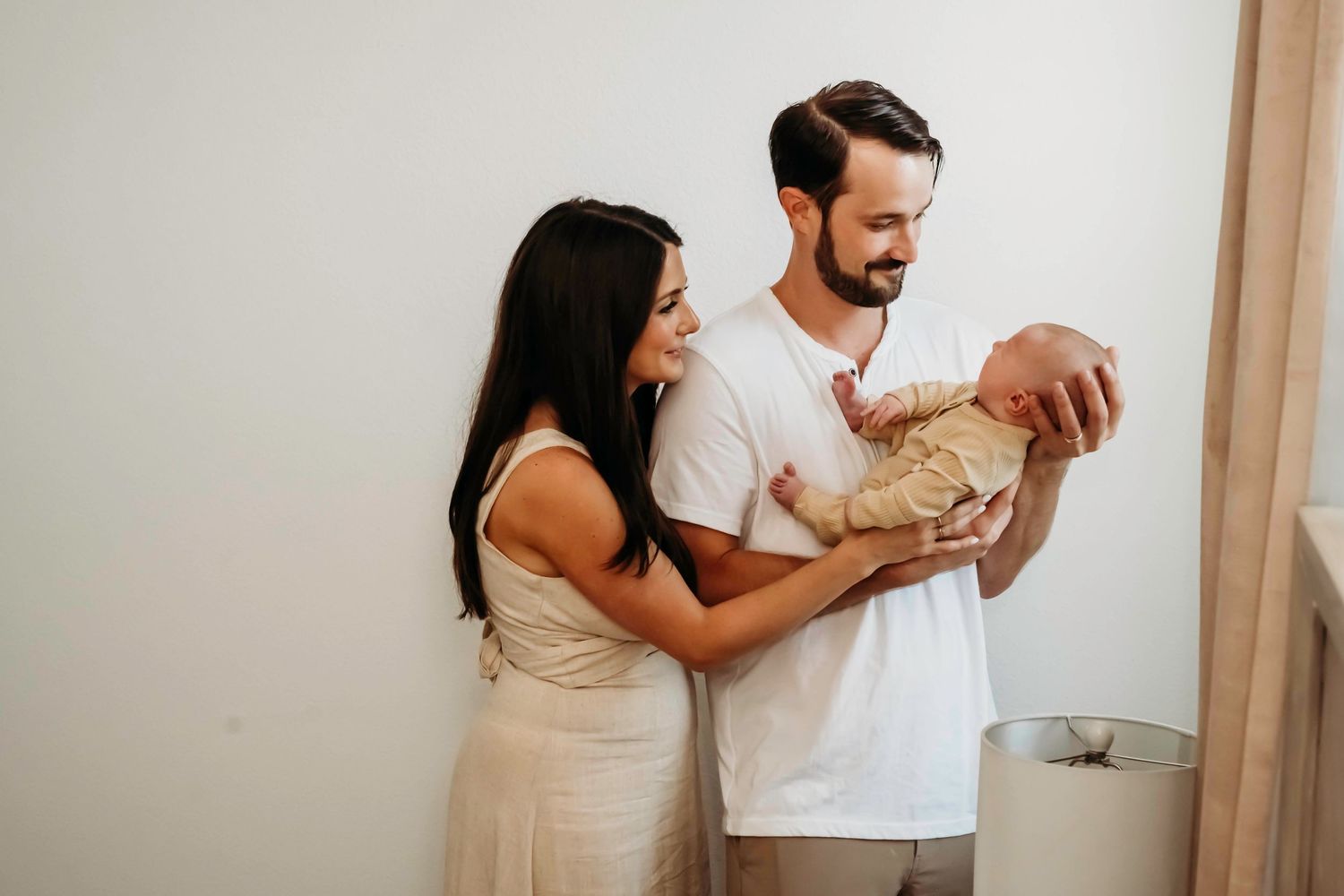 Parents bonding with their newborn baby while sitting together on a couch at home.